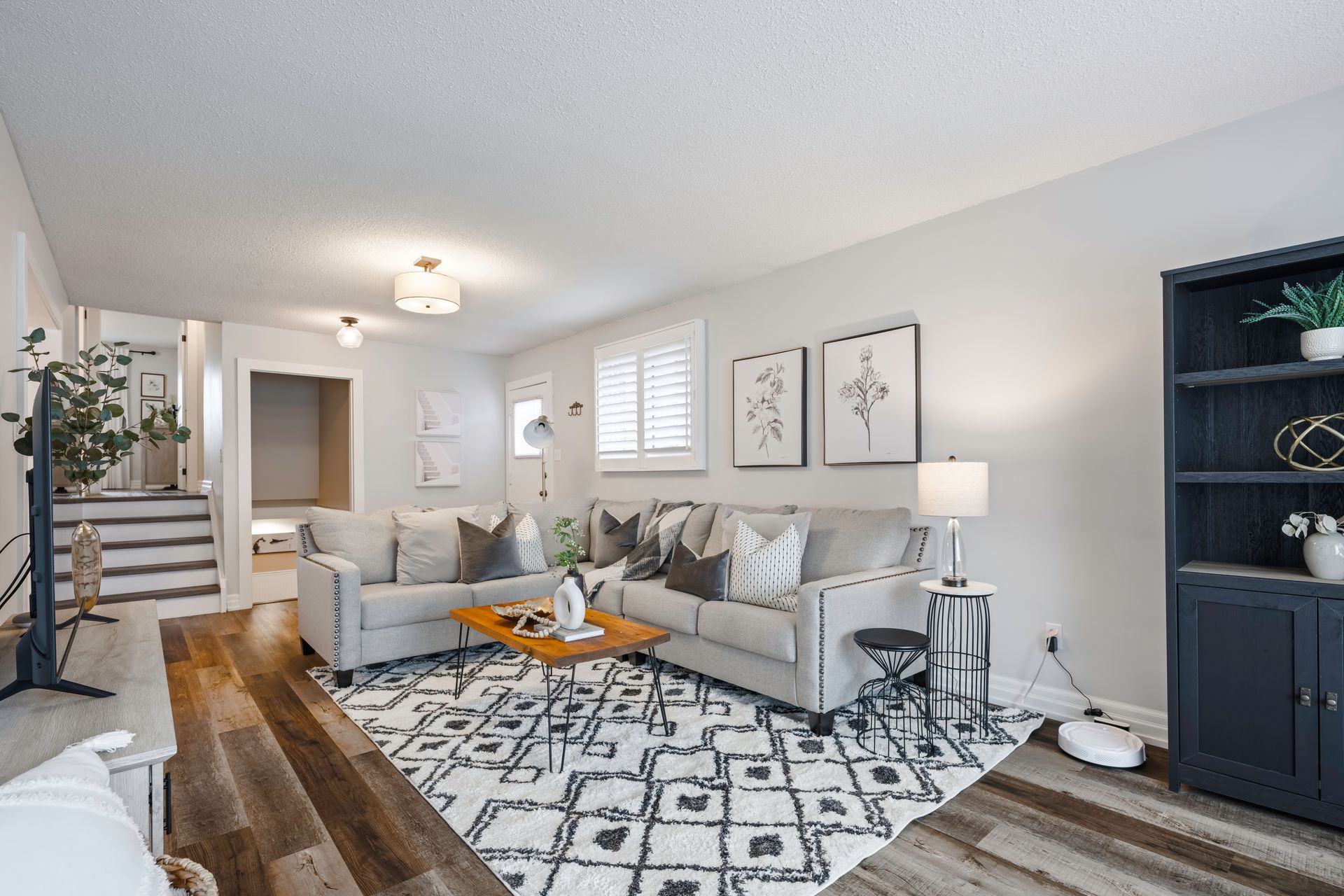 A living room with a couch , rug , coffee table and stairs.