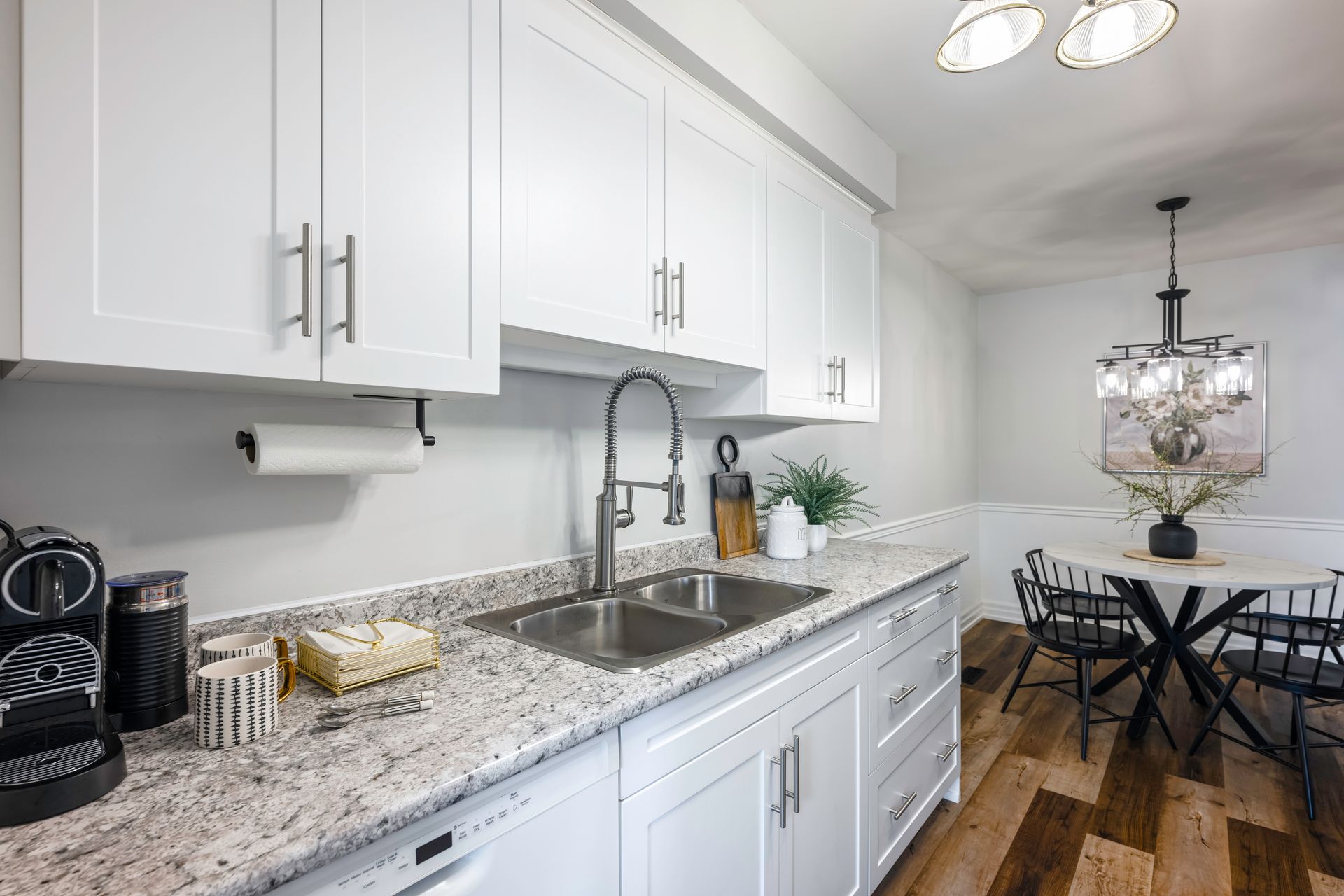 A kitchen with white cabinets , granite counter tops , a sink and a dishwasher.
