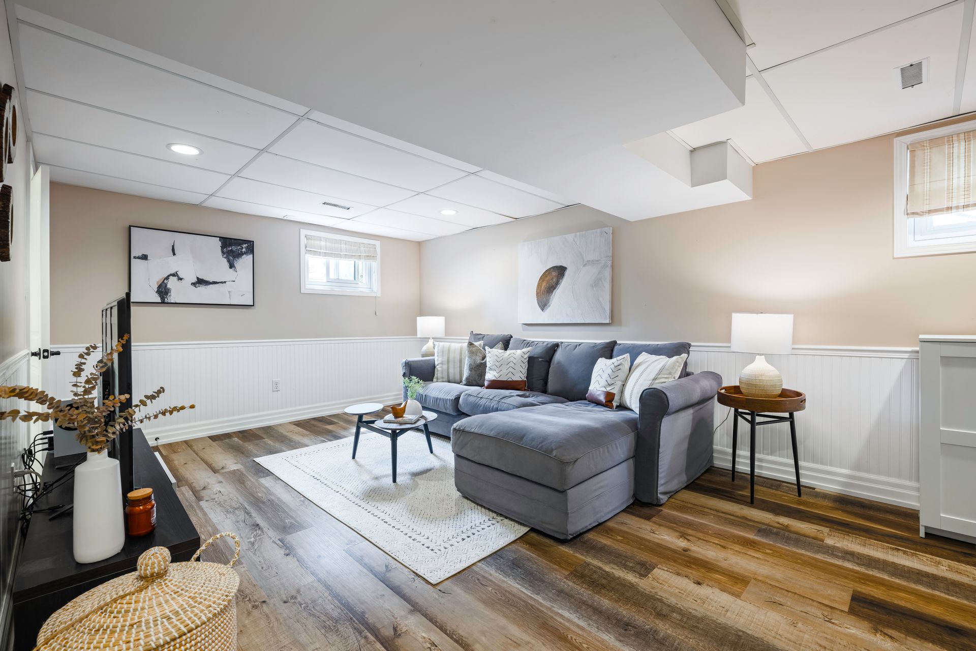 A living room in a basement with a couch and a television.