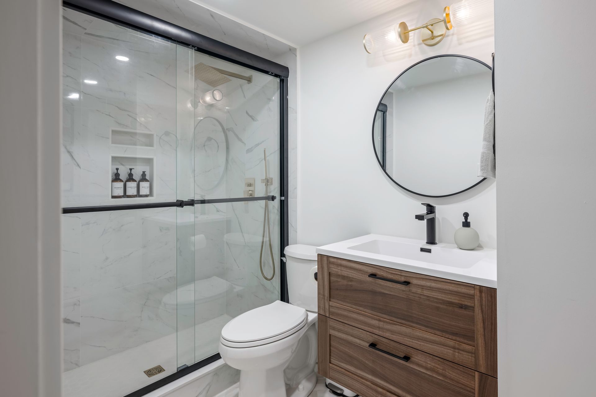 A bathroom with a toilet , sink , shower and mirror.