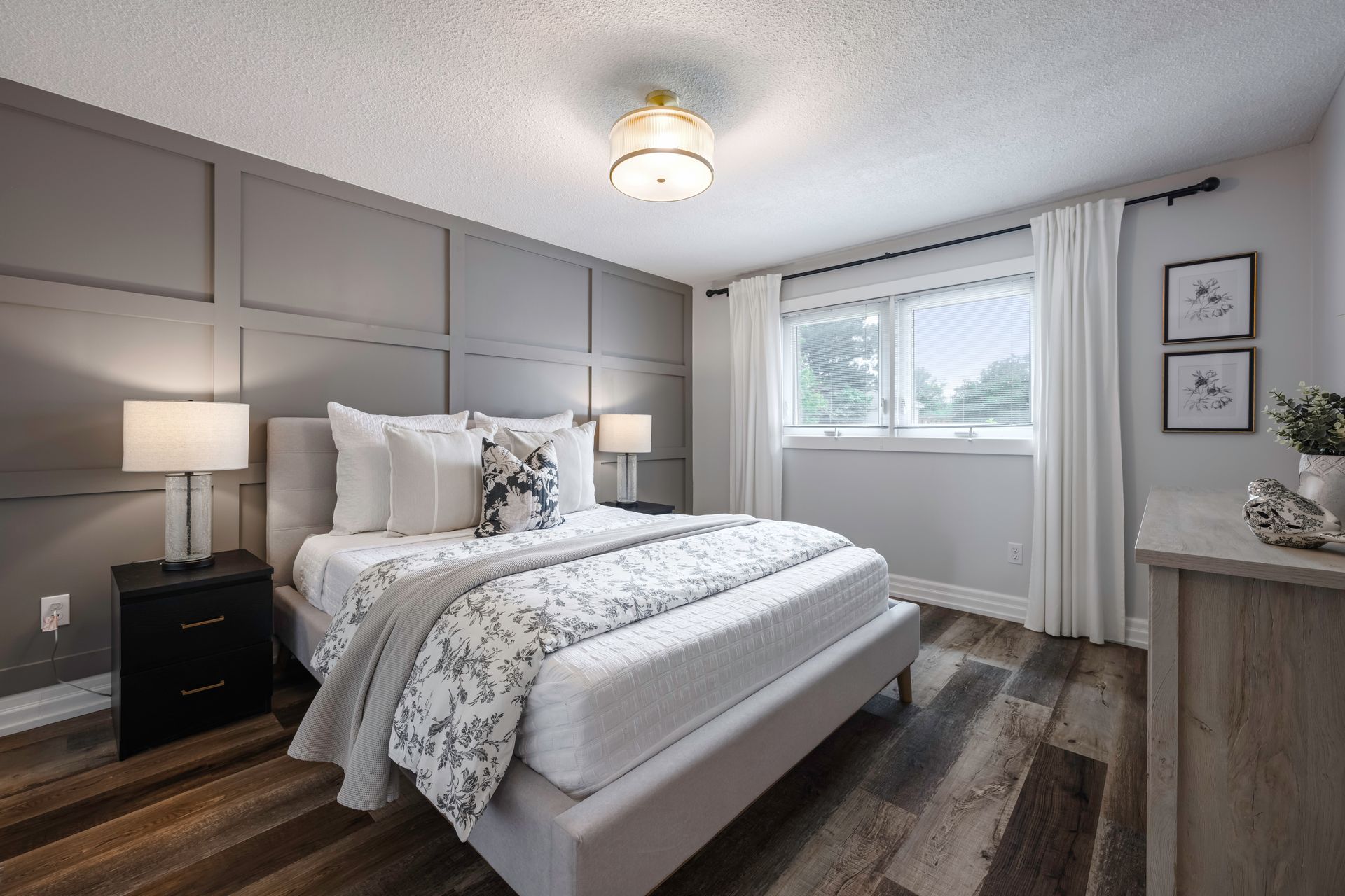 A bedroom with a bed , nightstand , dresser and window.