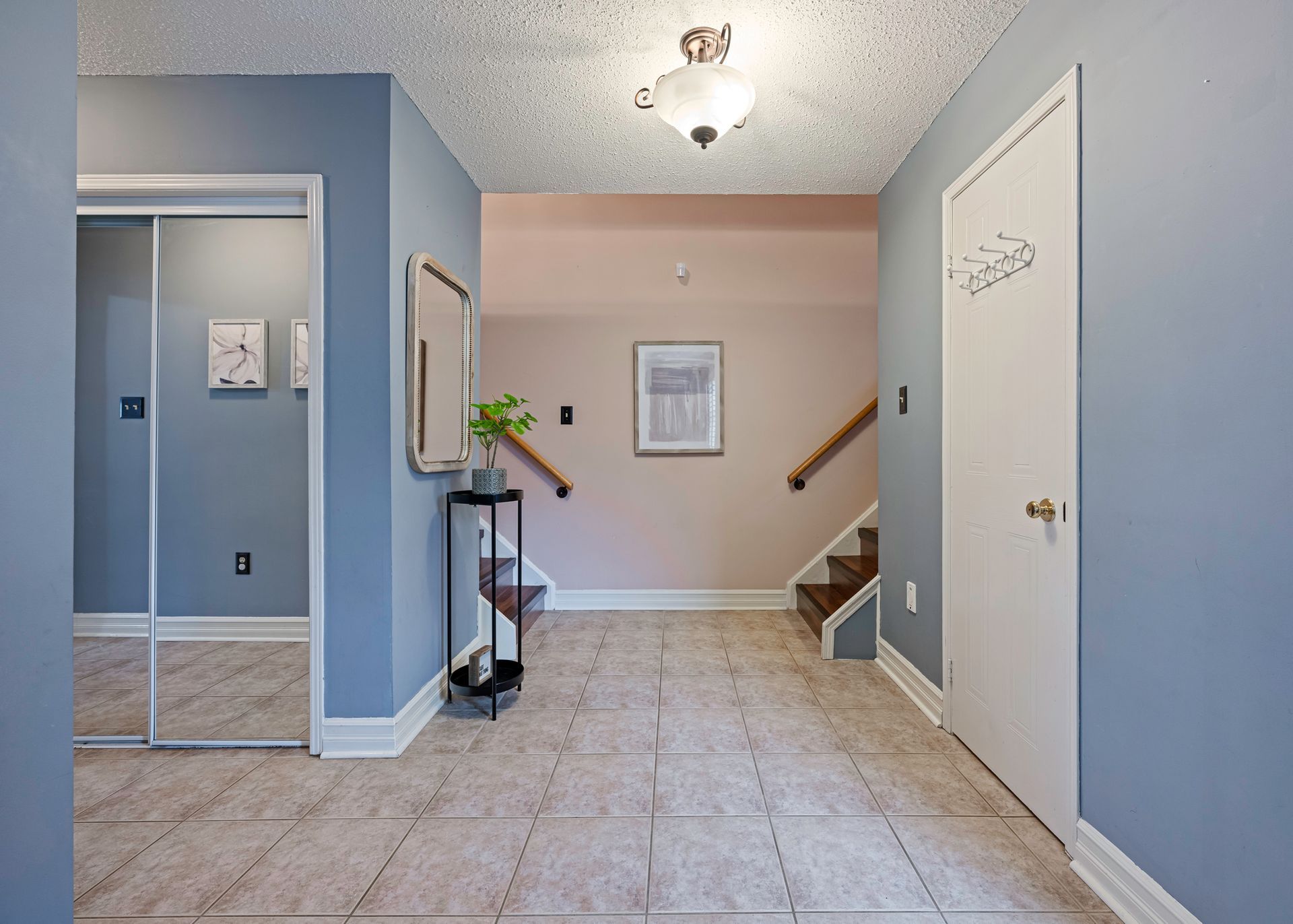 A hallway in a house with stairs and a mirror