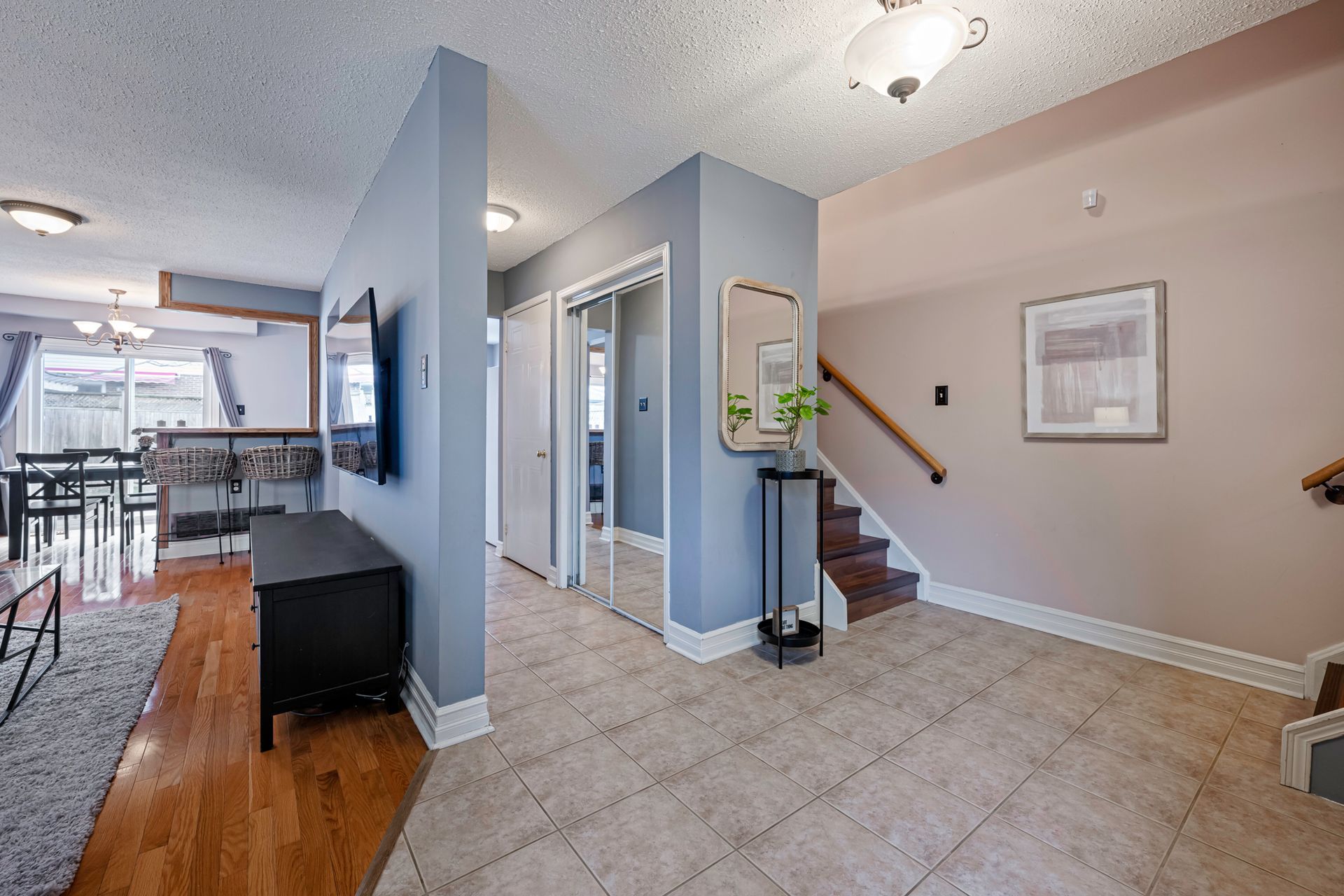 A hallway in a house with hardwood floors and stairs leading up to the second floor.