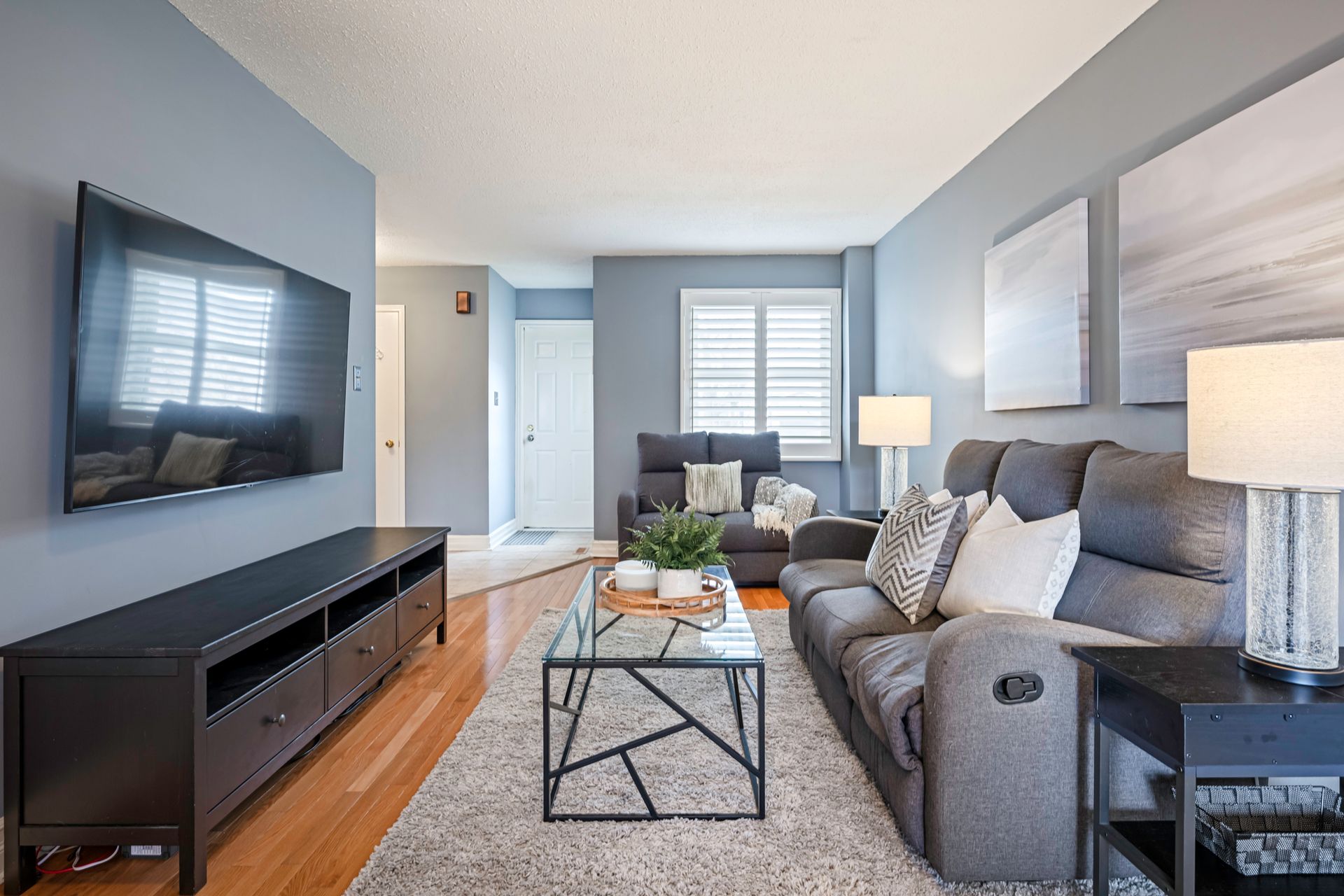 A living room with a couch and a flat screen tv on the wall.