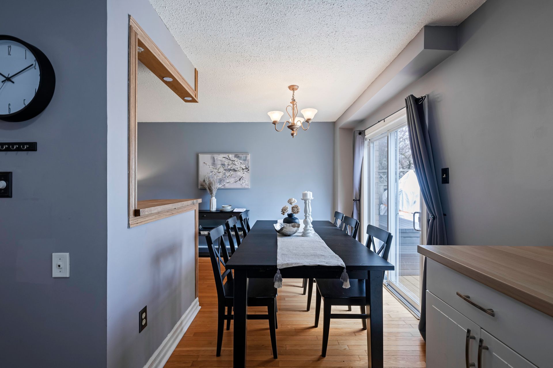 A dining room with a table and chairs and a clock on the wall