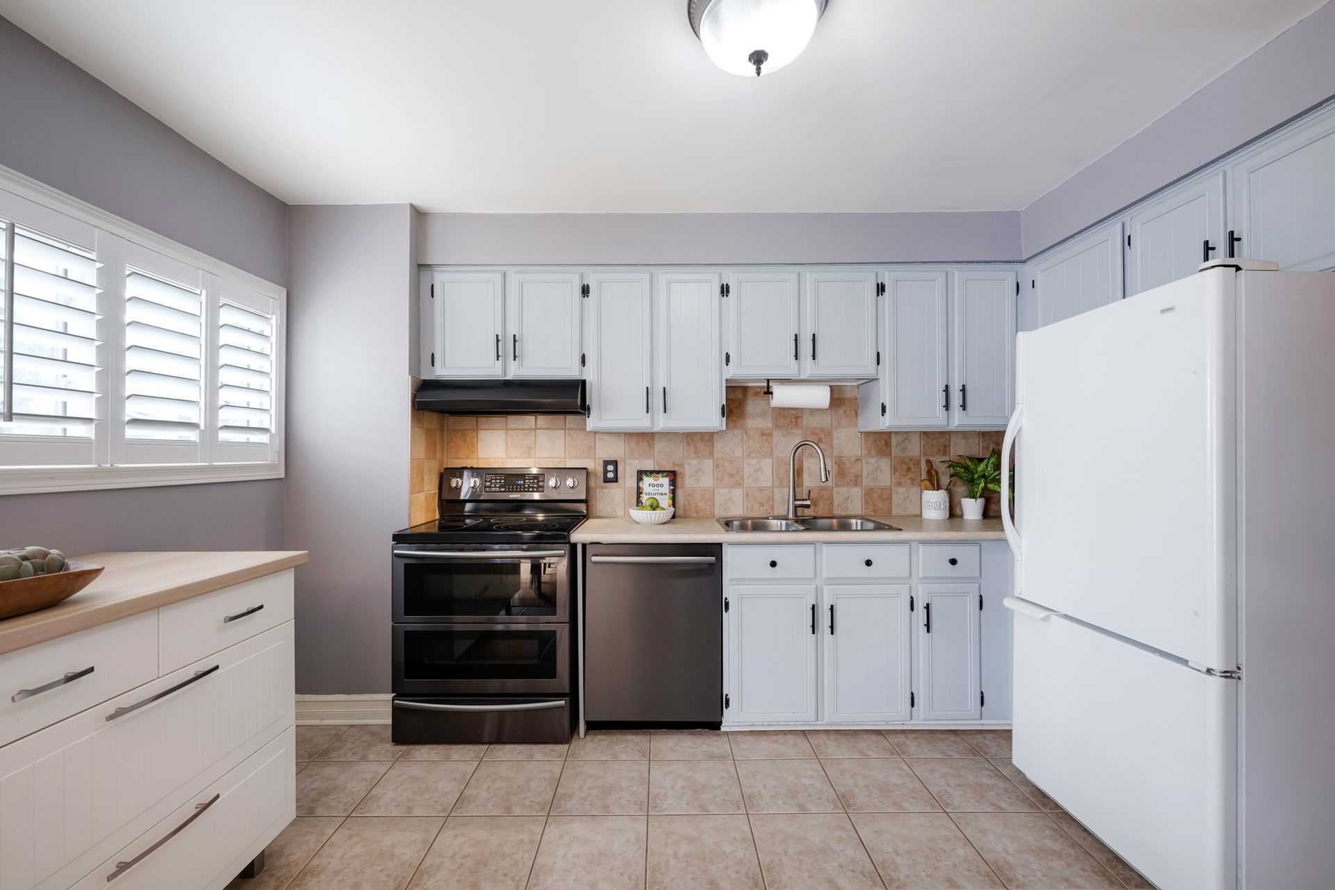 A kitchen with white cabinets and a white refrigerator