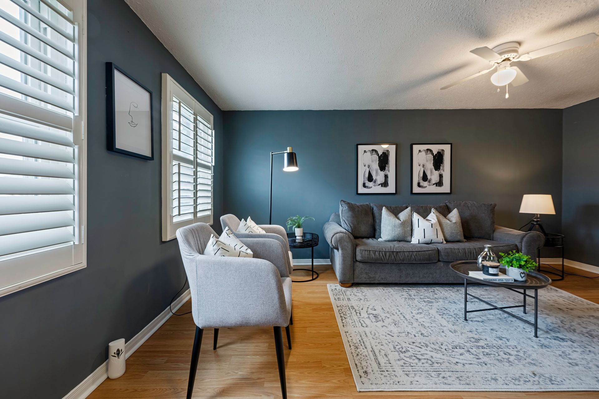 A living room with a couch , chairs , a coffee table and a ceiling fan.