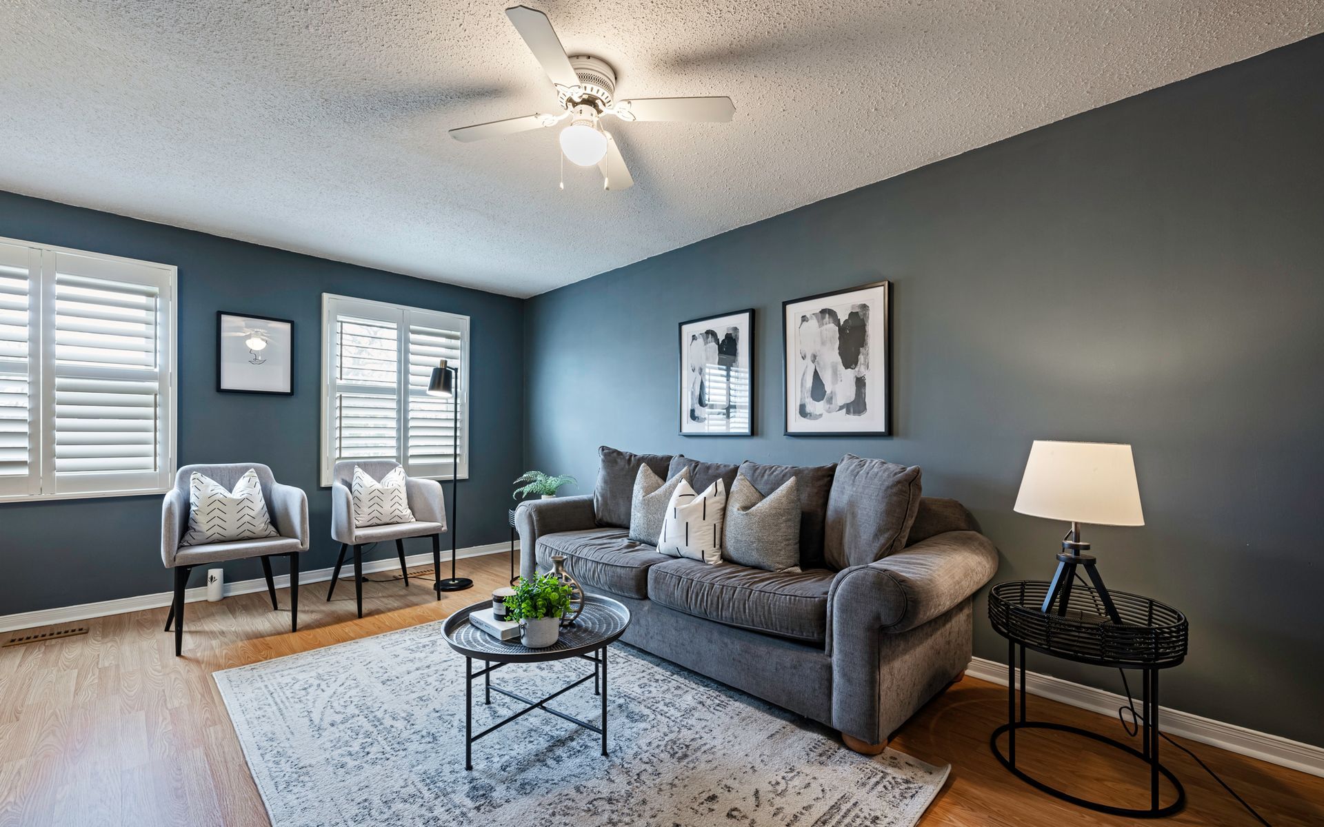 A living room with a couch , chairs , a coffee table and a ceiling fan.
