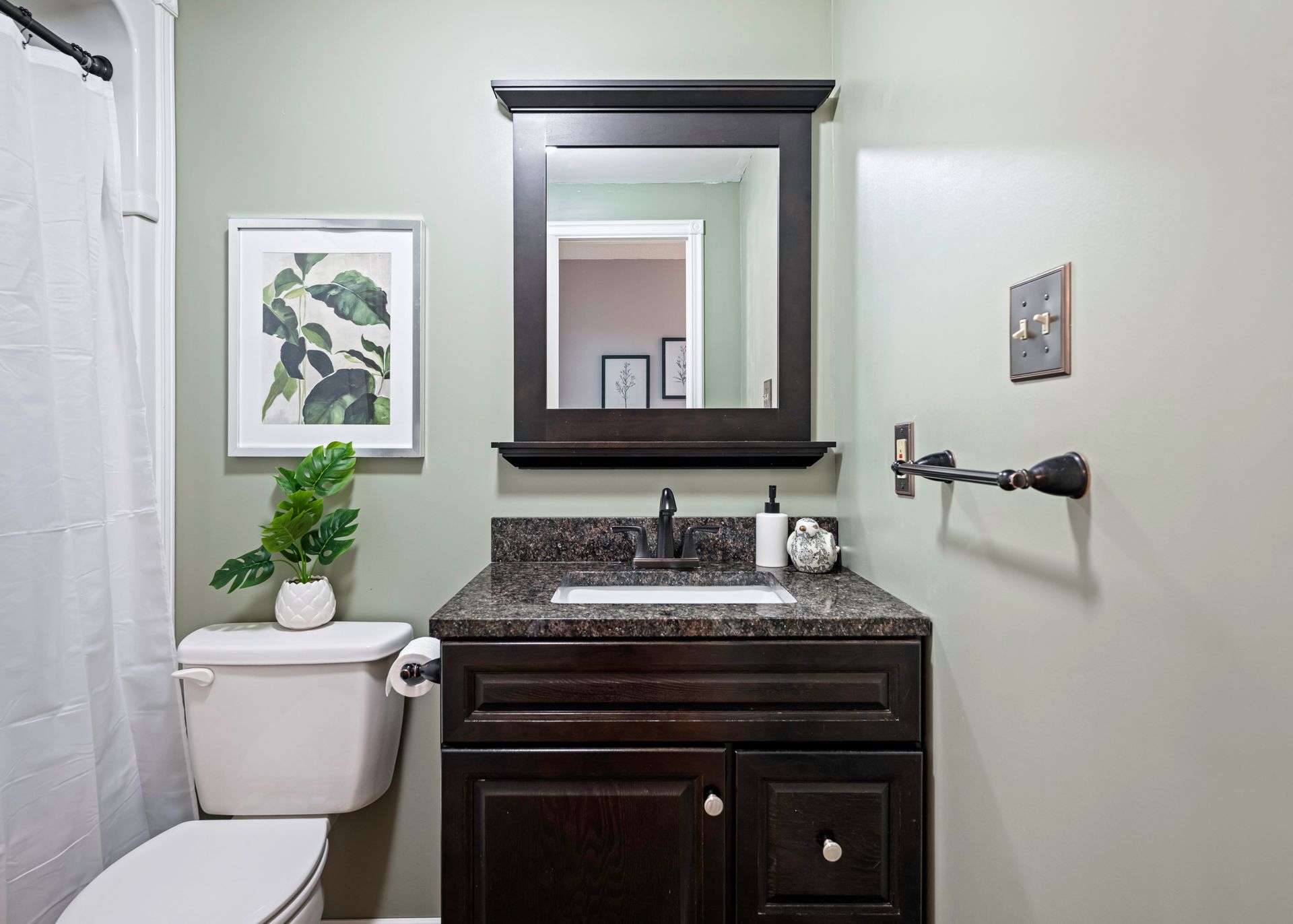 A bathroom with a toilet , sink and mirror.