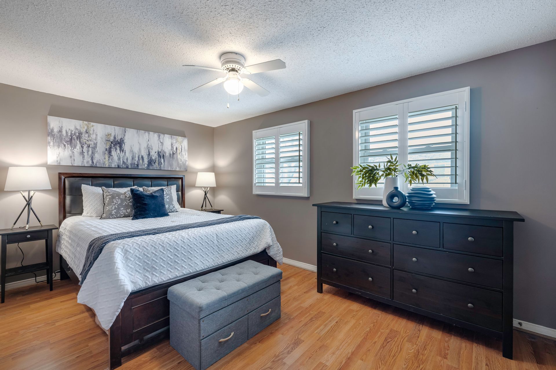 A bedroom with a bed , dresser , nightstand , and ceiling fan.