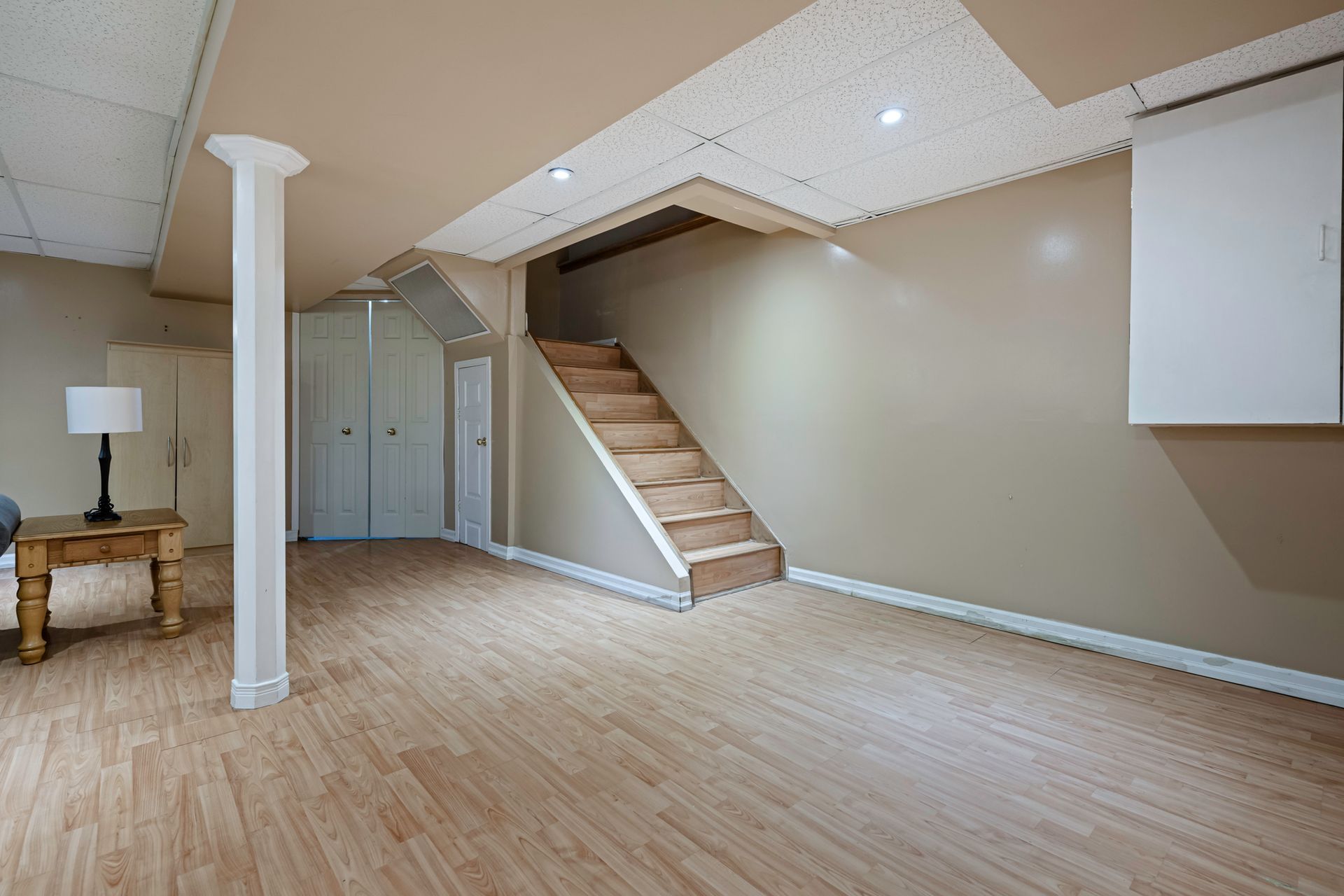 A basement with hardwood floors and stairs leading up to the second floor.