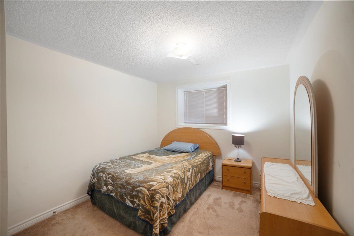 A bedroom with a single bed , nightstand , mirror and lamp.