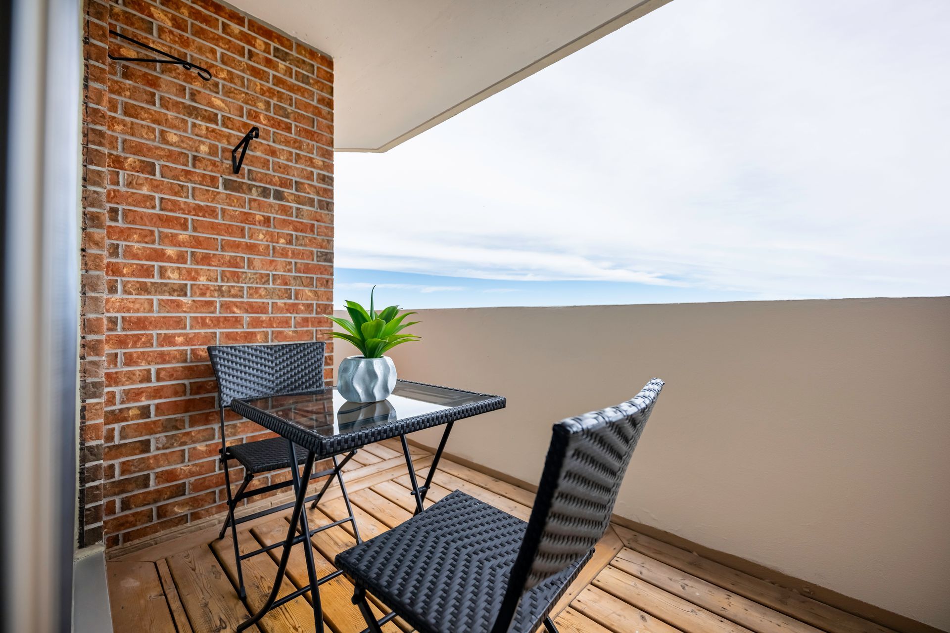 A balcony with a table and chairs and a brick wall.