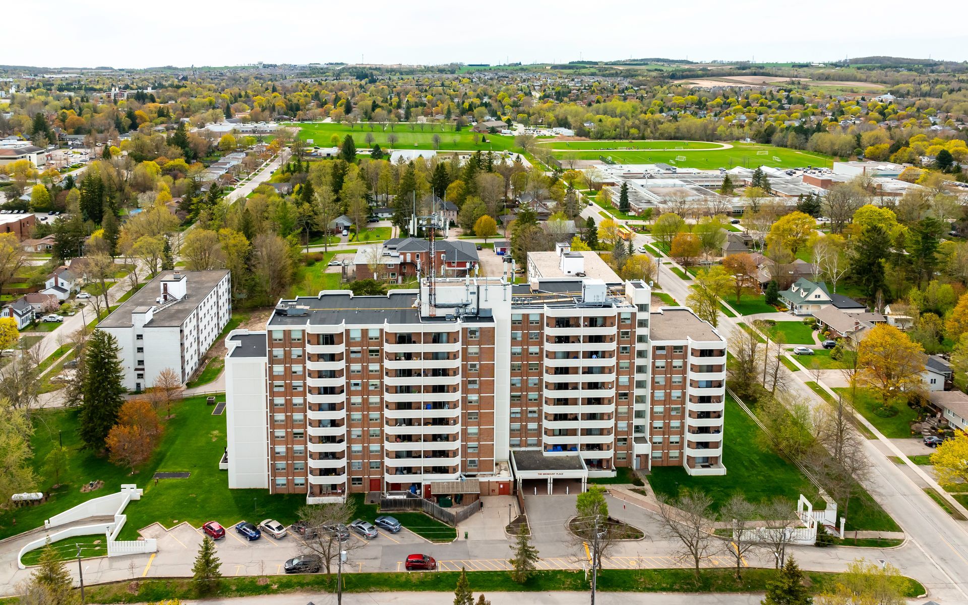 An aerial view of a large apartment building in a city surrounded by trees.