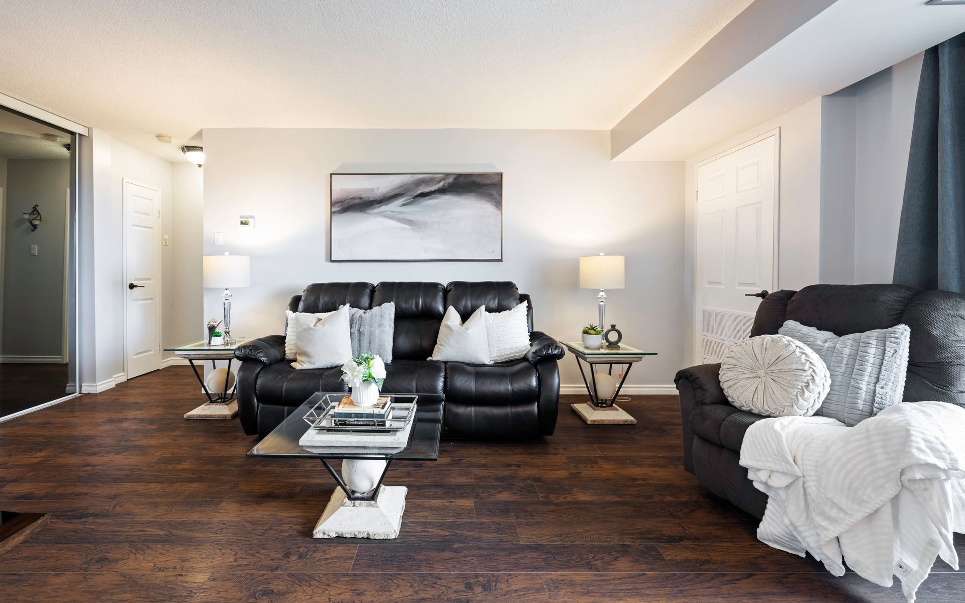 A living room with a couch , chair , coffee table and a painting on the wall.