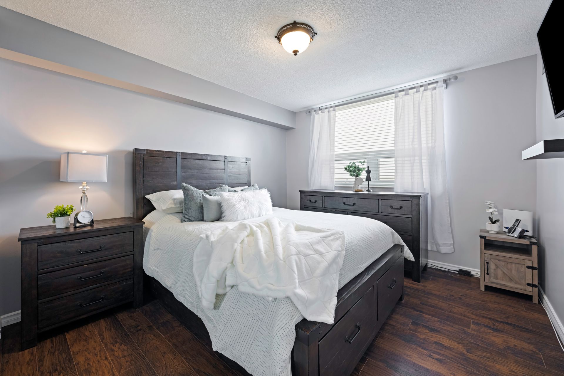 A bedroom with a bed , dresser , nightstand and television.