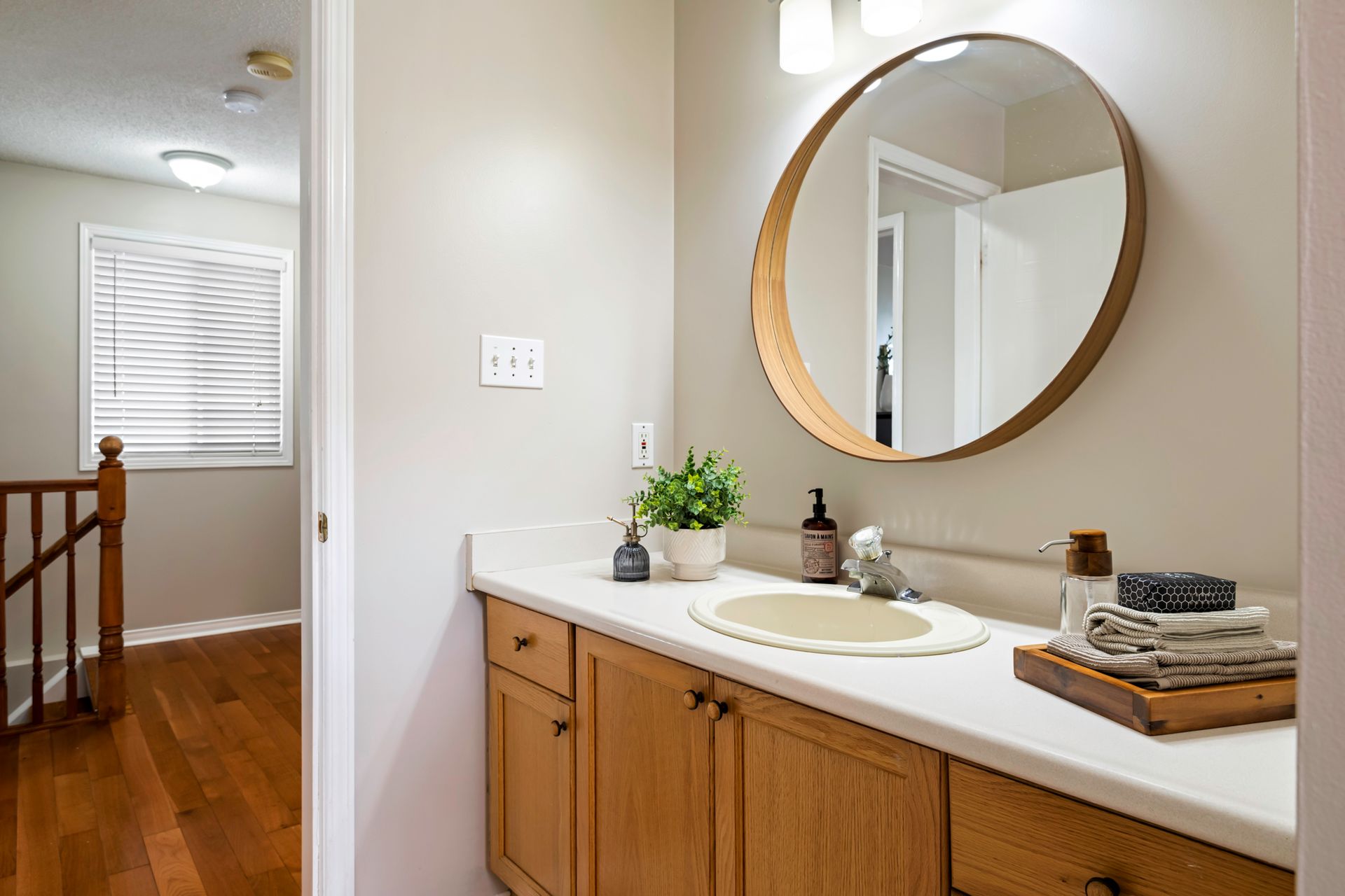 A bathroom with a sink , mirror and wooden cabinets.