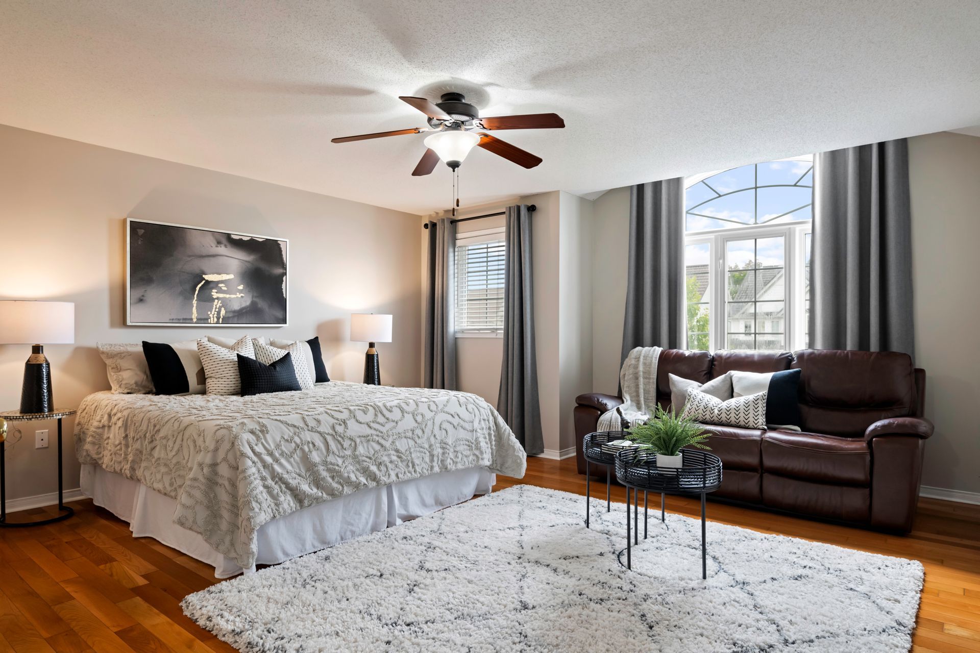 A bedroom with a king size bed , a couch , and a ceiling fan.