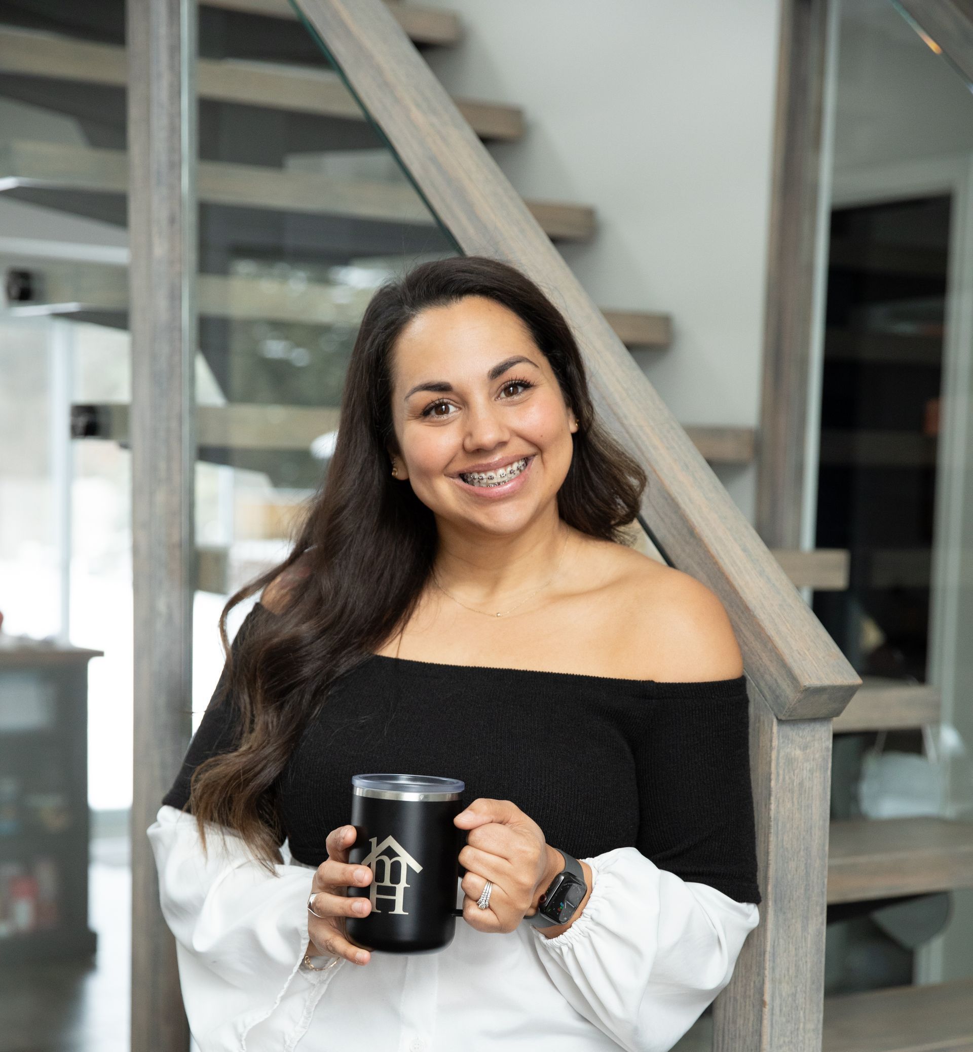 A woman is standing on a set of stairs holding a cup of coffee.