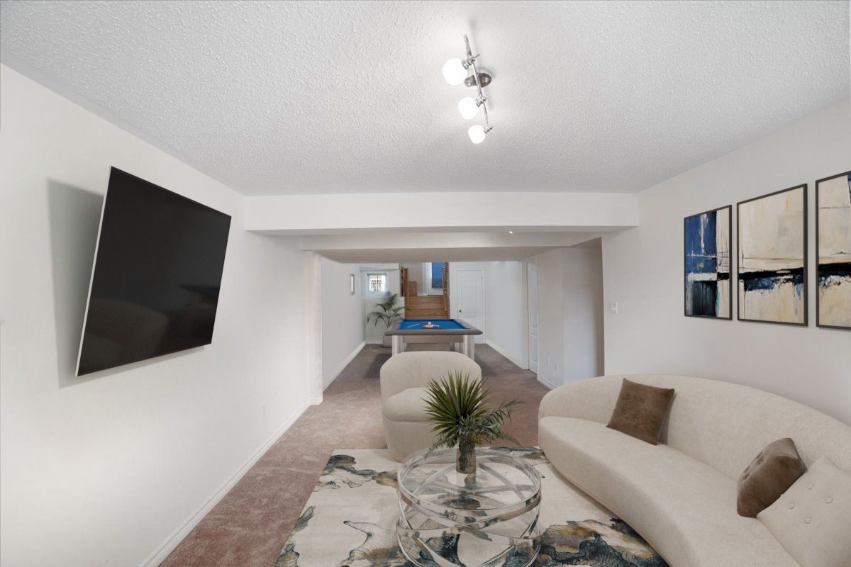 A living room with a couch and a flat screen tv on the wall.