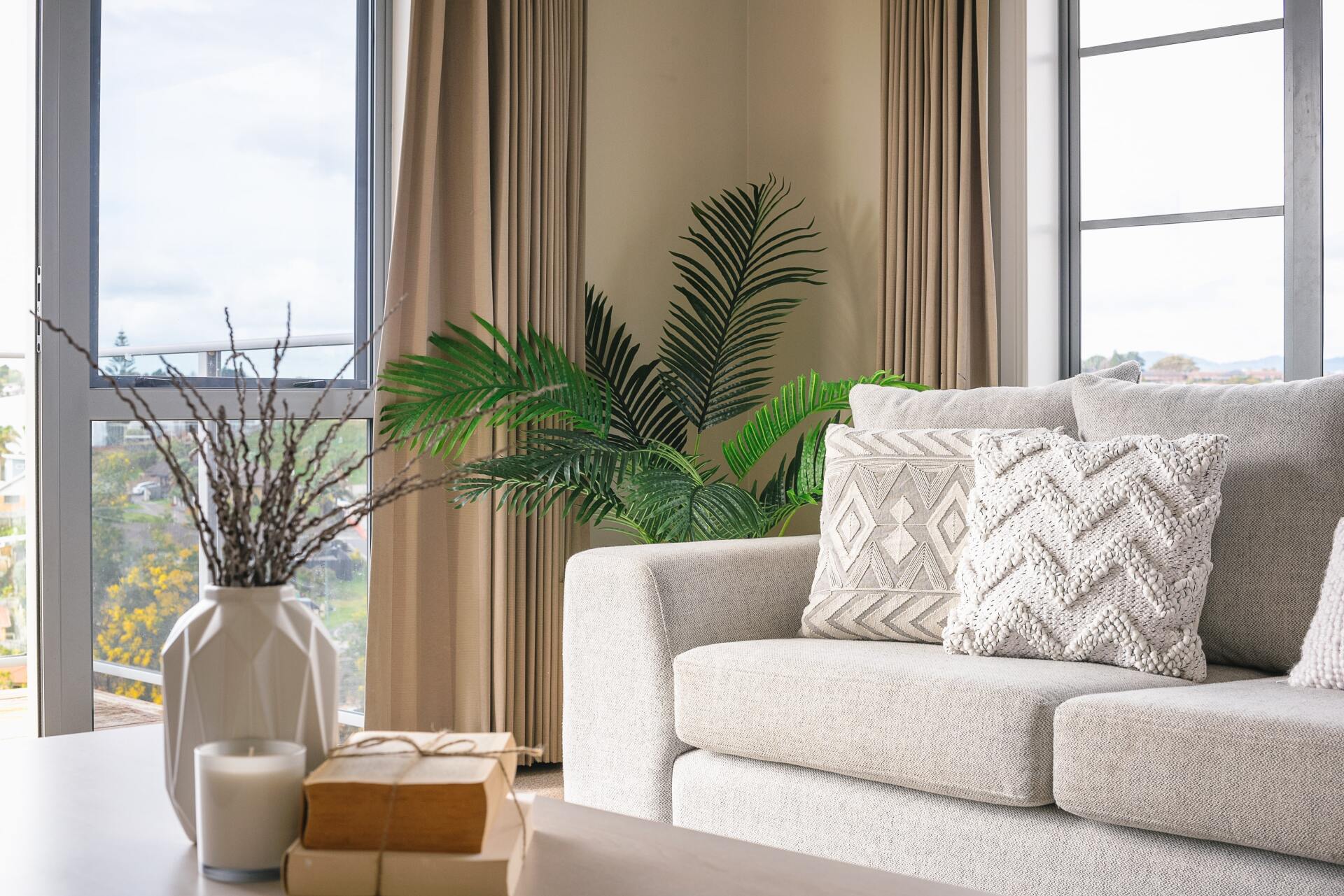 A living room with a couch , table , vases and a window.