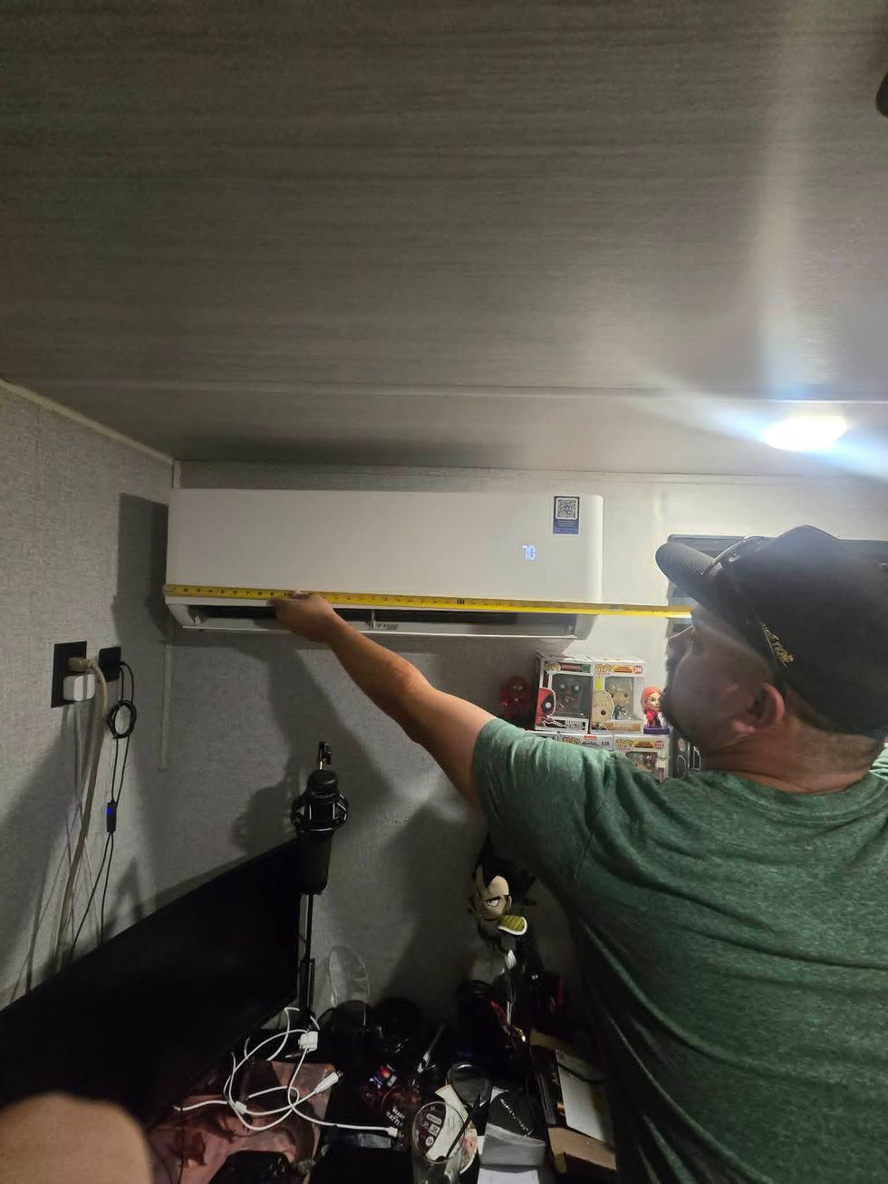 Person using a level to measure a wall-mounted cabinet in a cluttered room