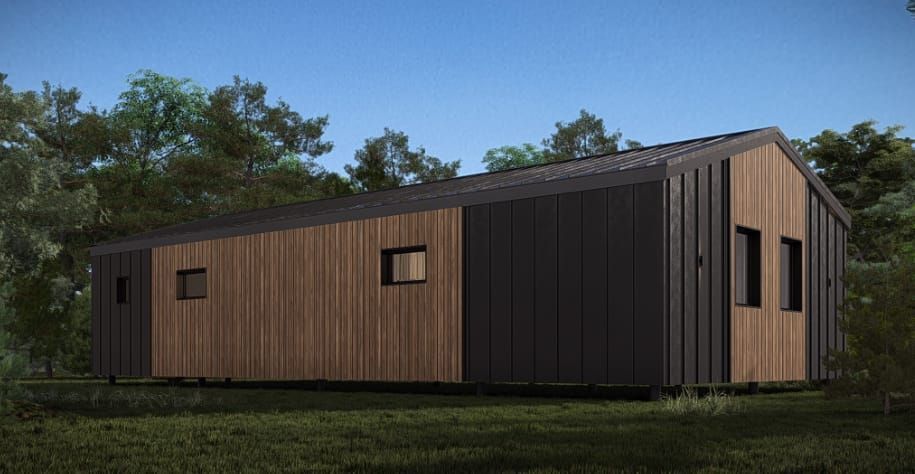 Modern cabin with wooden and black siding, small windows, set in a grassy area with trees.