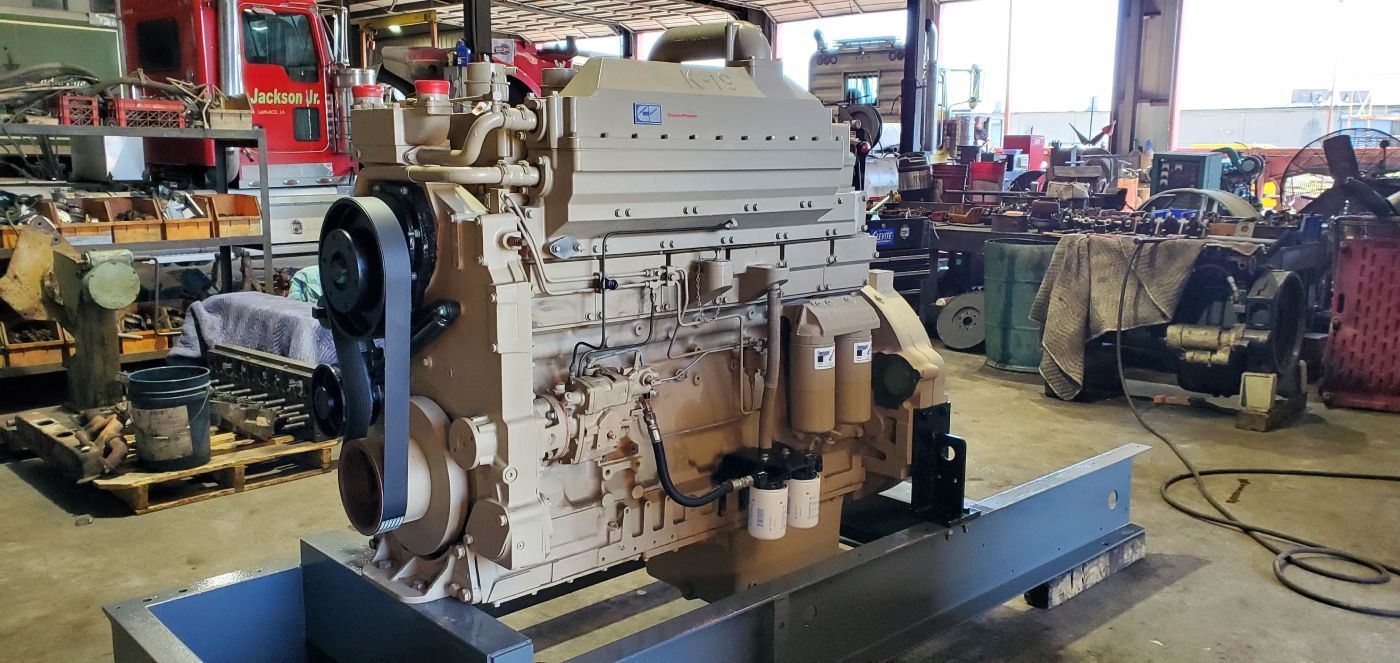 Large industrial engine mounted on a blue metal base in a warehouse workshop | S&V Diesel Repair