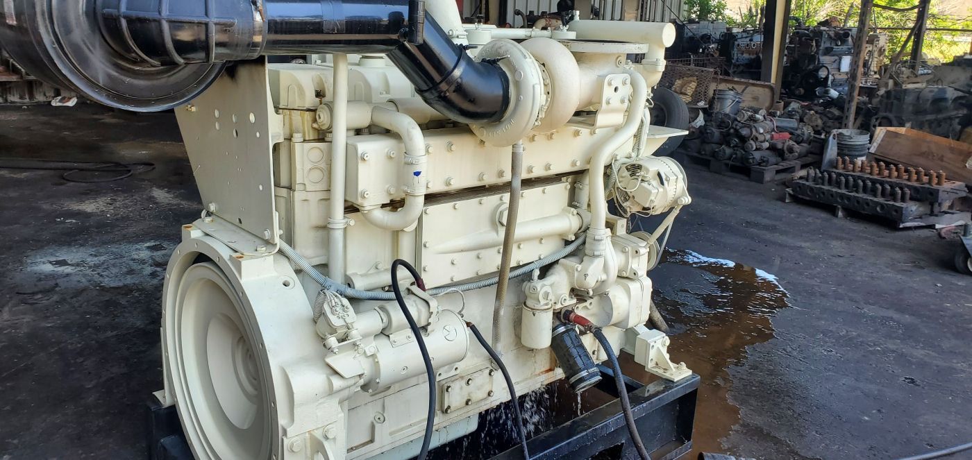Large beige industrial engine on a workshop floor, shown in side view with hoses and cables attached. | S&V Diesel Repair