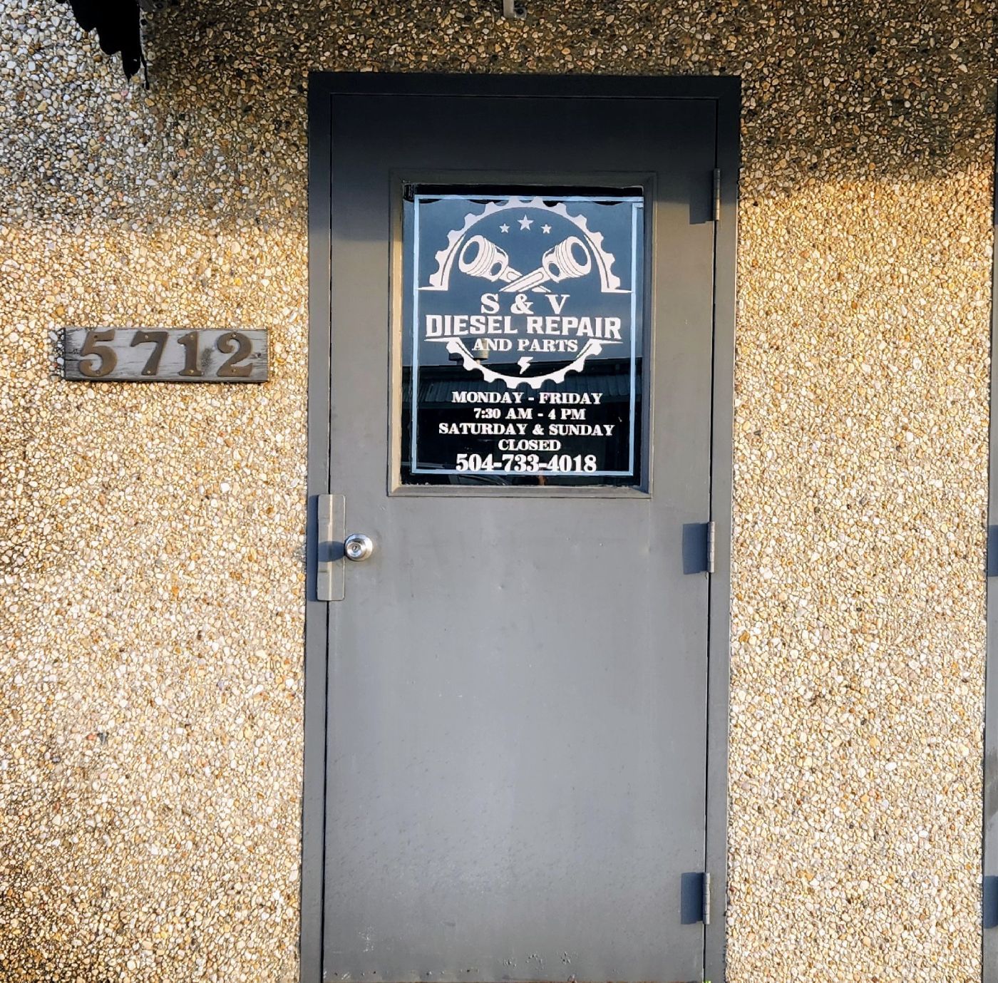 Gray door with diesel repair sign and address 5712 on a textured yellow wall | S&V Diesel Repair