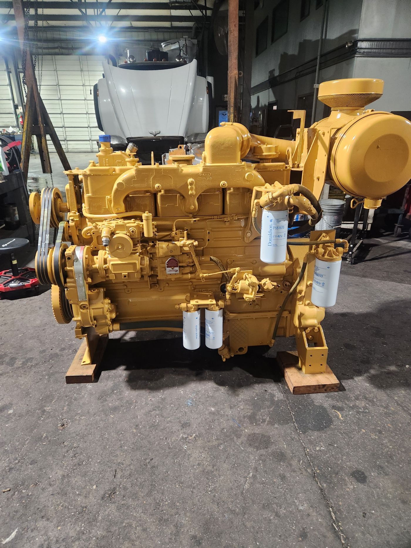 Yellow industrial generator or engine on a warehouse floor, with white filters and a large circular housing. | S&V Diesel Repair