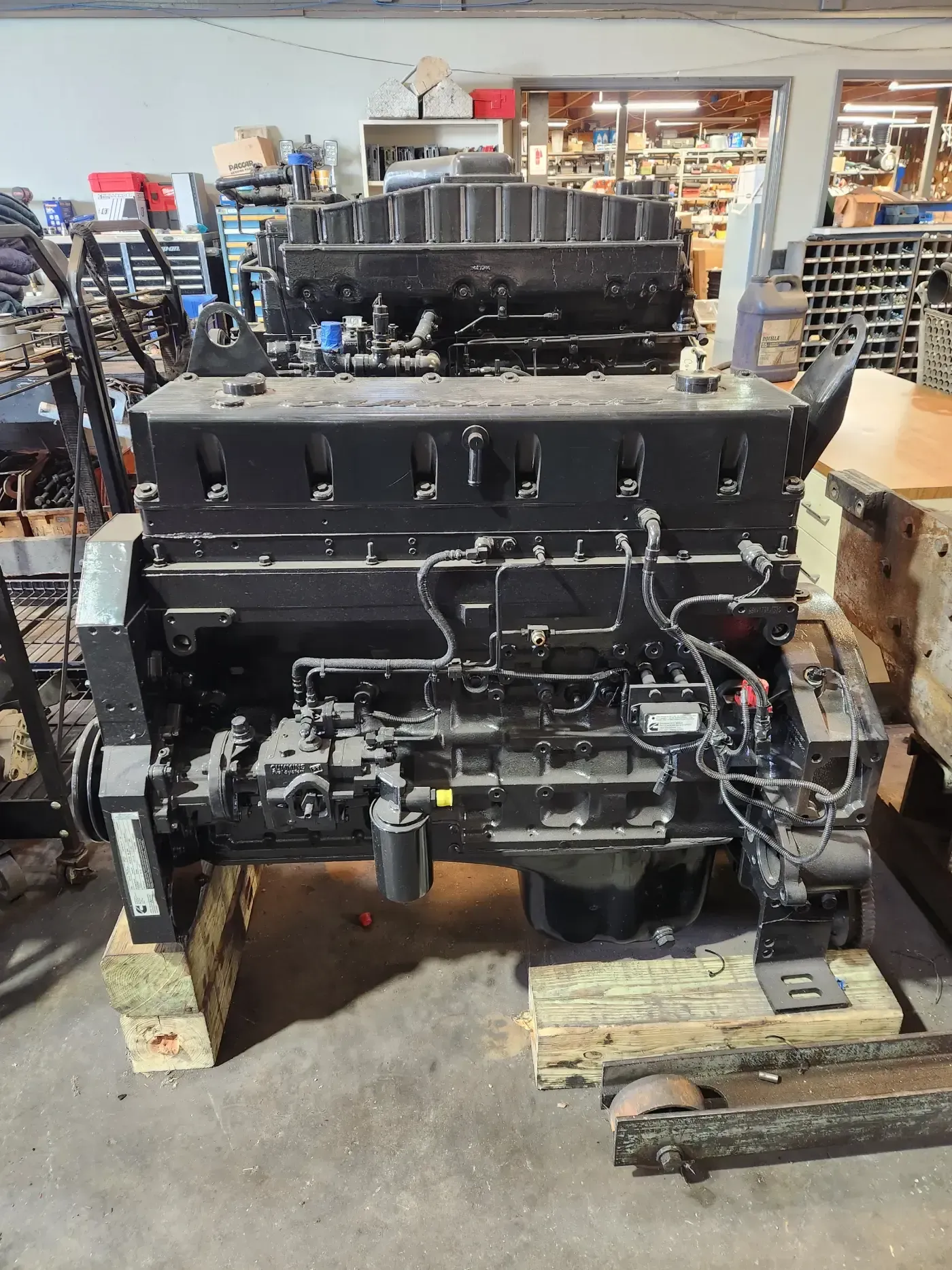 Large black industrial engine or machinery unit on wooden pallets in a workshop | S&V Diesel Repair