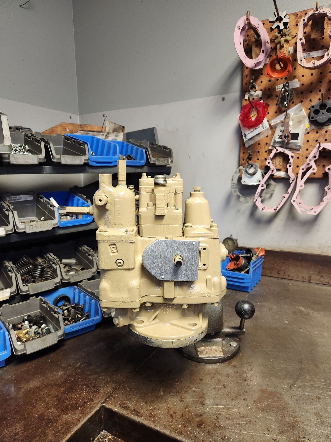 Beige industrial engine on a workshop floor beside tool bins and hanging hoses | S&V Diesel Repair