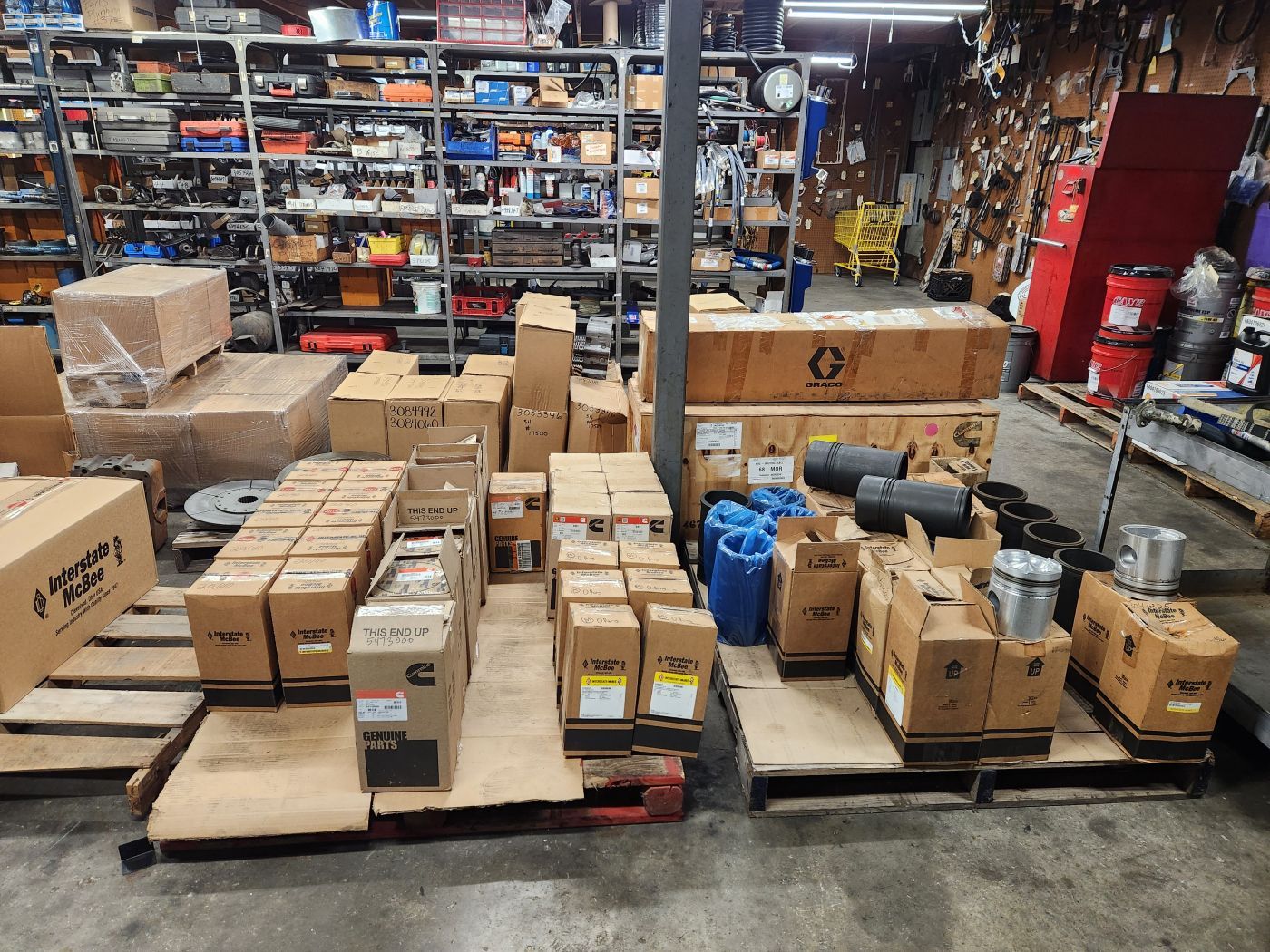 Pallets of boxed goods and shipping packages stacked in a warehouse aisle. | S&V Diesel Repair