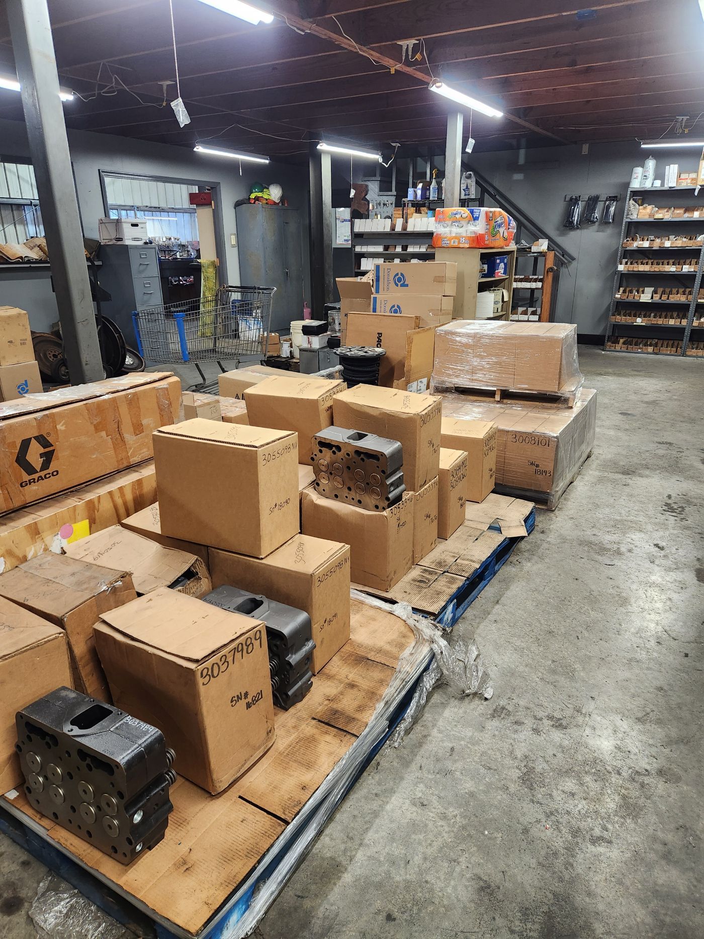 Warehouse aisle with stacked cardboard boxes on pallets and shelves in the background | S&V Diesel Repair