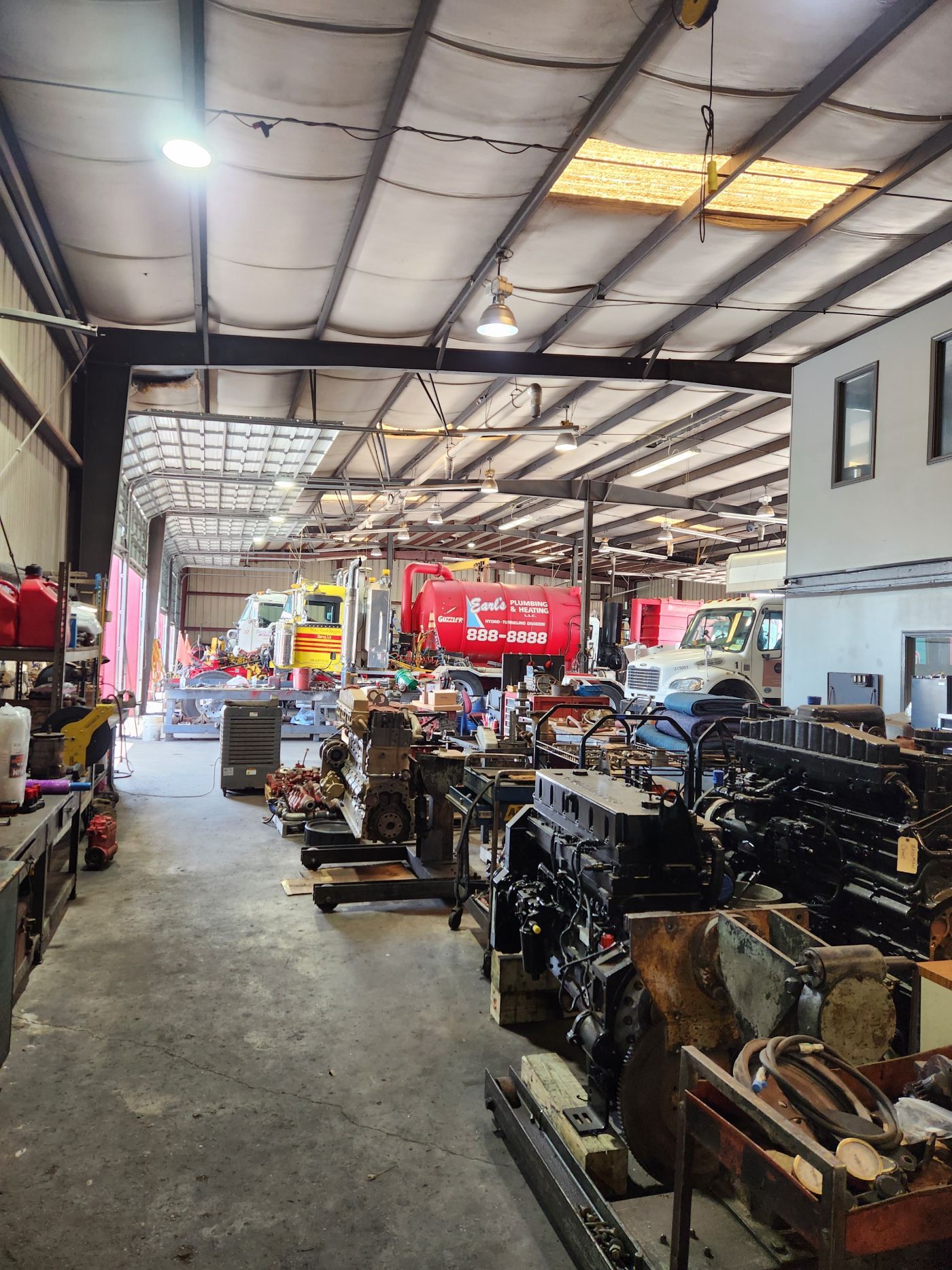 Indoor workshop with rows of machinery under a metal roof and bright overhead lights | S&V Diesel Repair