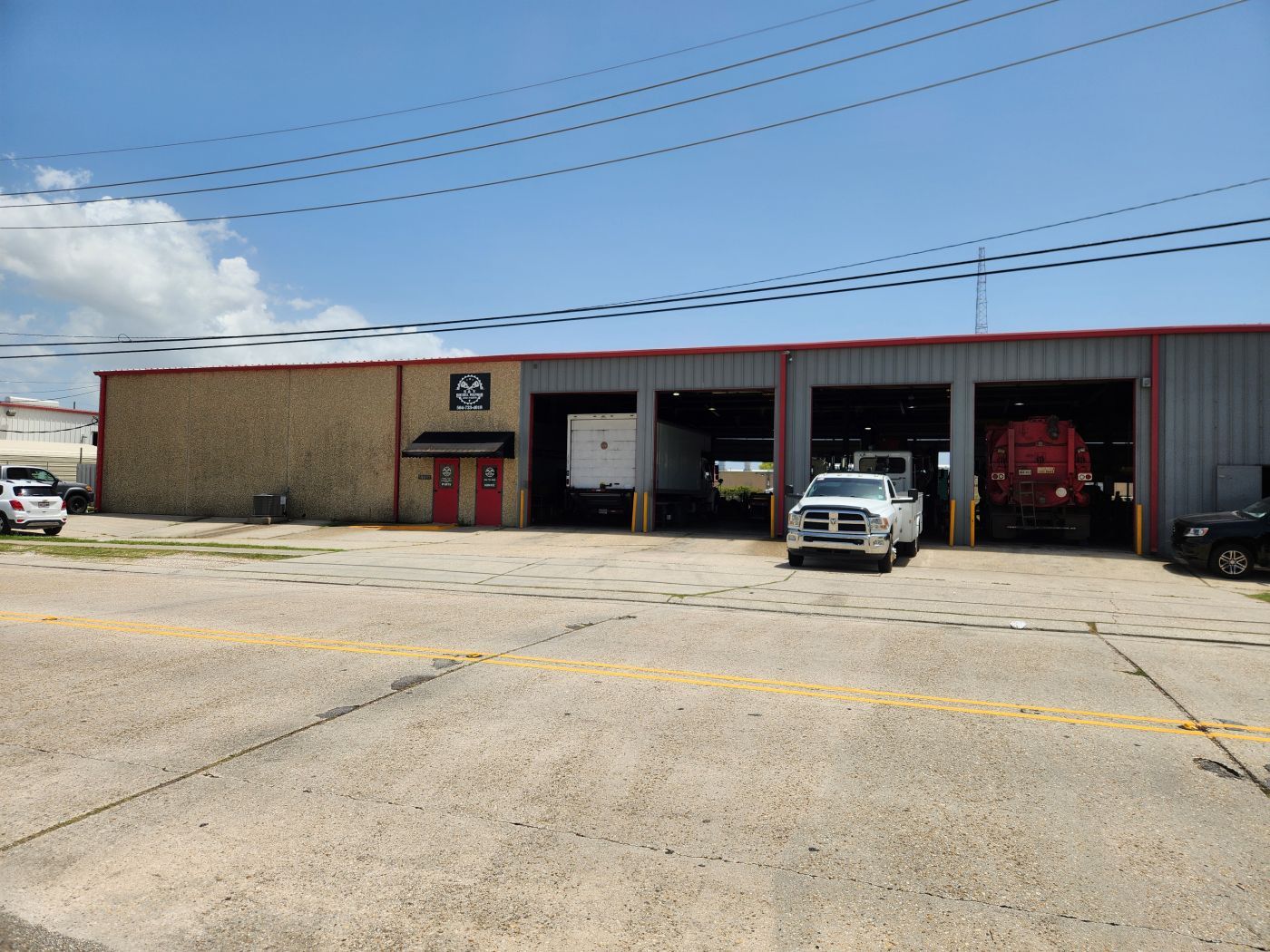 Auto repair shop with open garage bays, a white SUV parked outside, and a red vehicle inside | S&V Diesel Repair