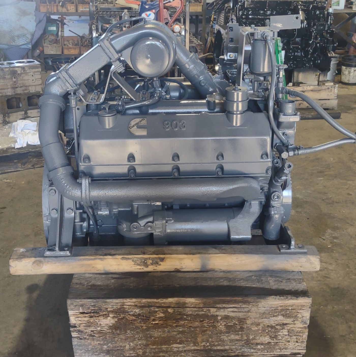 Gray industrial engine mounted on a wooden pallet in a warehouse, with metal piping and components attached | S&V Diesel Repair