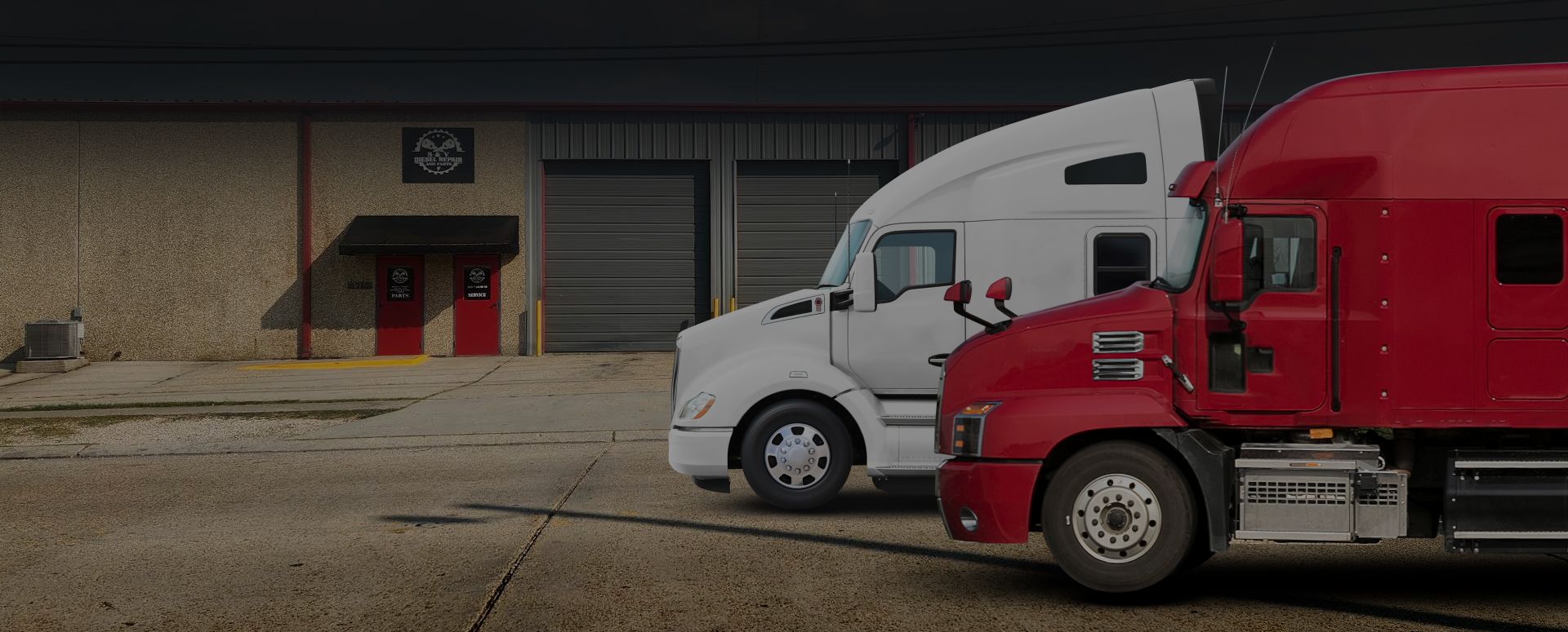 Red and white semi trucks parked outside a warehouse loading dock | S&V Diesel Repair