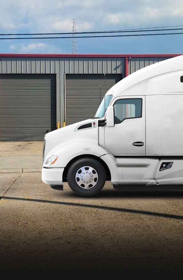 White semi-truck parked in front of a gray warehouse under a cloudy sky | S&V Diesel Repair