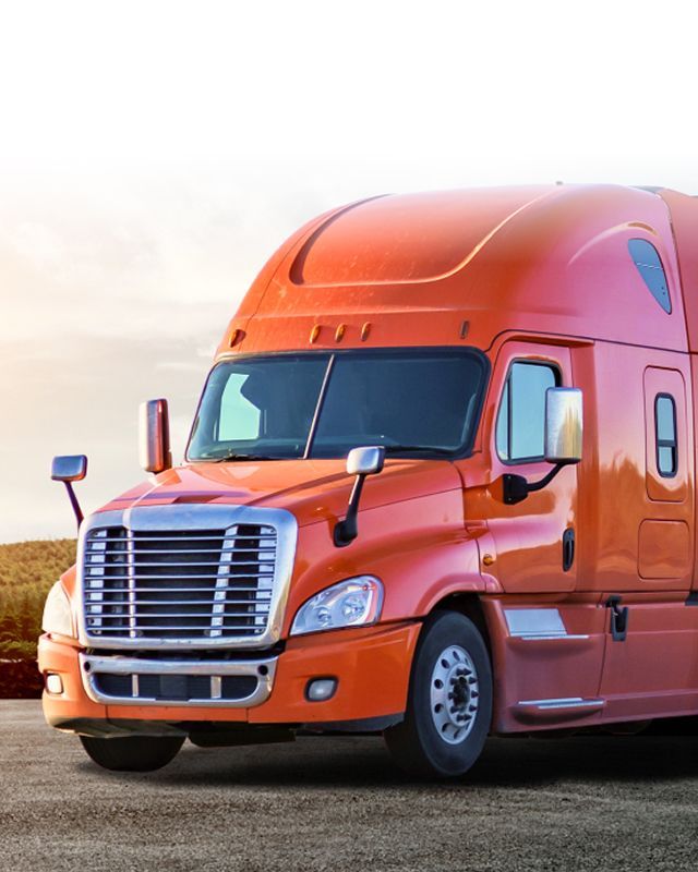 Orange semi-truck on a roadside at sunset, facing left. | S&V Diesel Repair