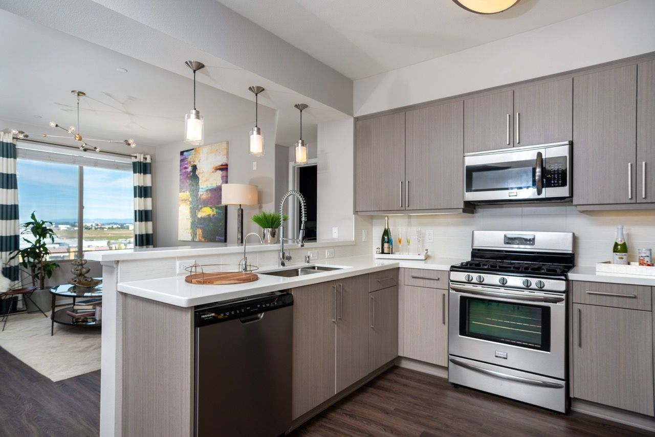 Modern apartment kitchen with stainless steel appliances and an open living area.