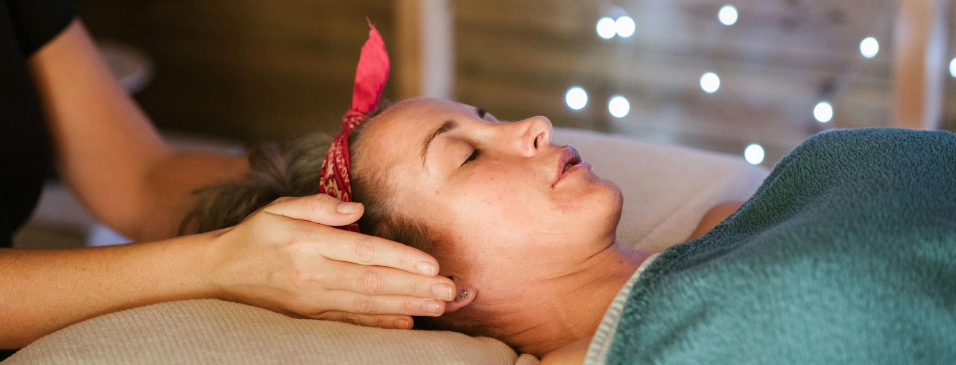 A woman is getting Reiki services with a hand hovering beside her ears
