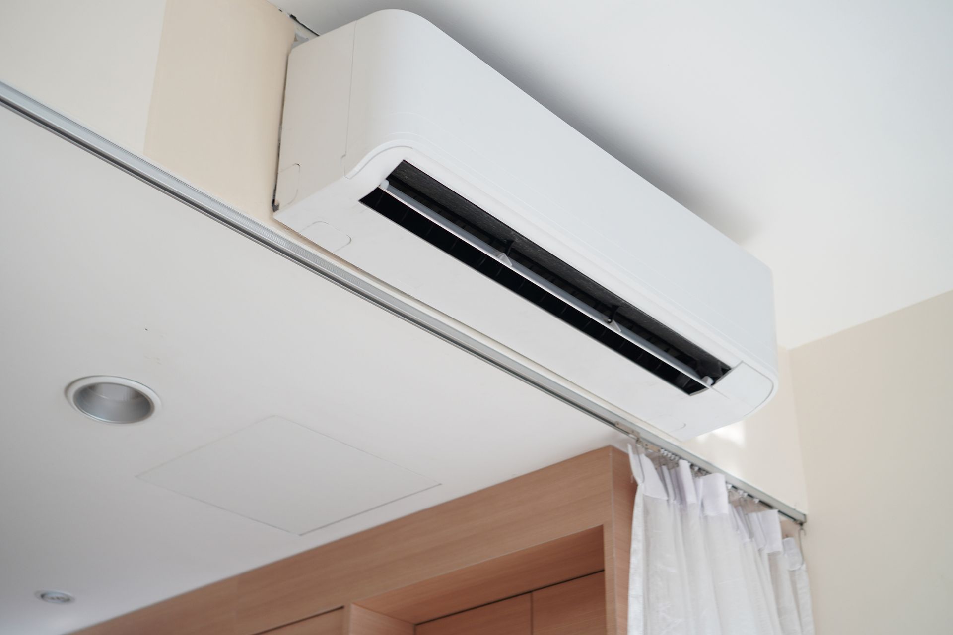 A room with a window and an air conditioner on the wall.