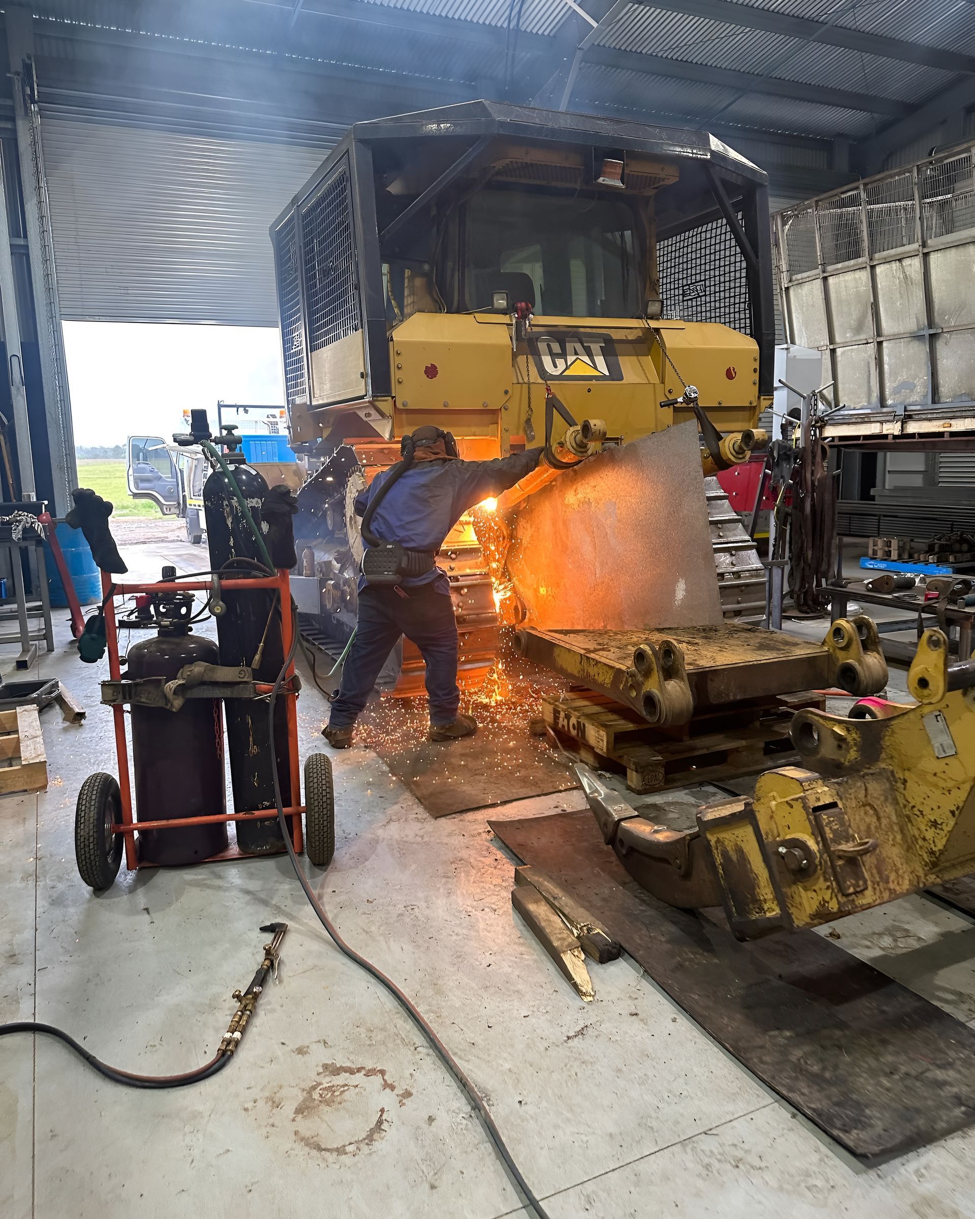 A Person Welding Metal on a Yellow Bulldozer — HOLESHOT Diesel In Gympie, QLD