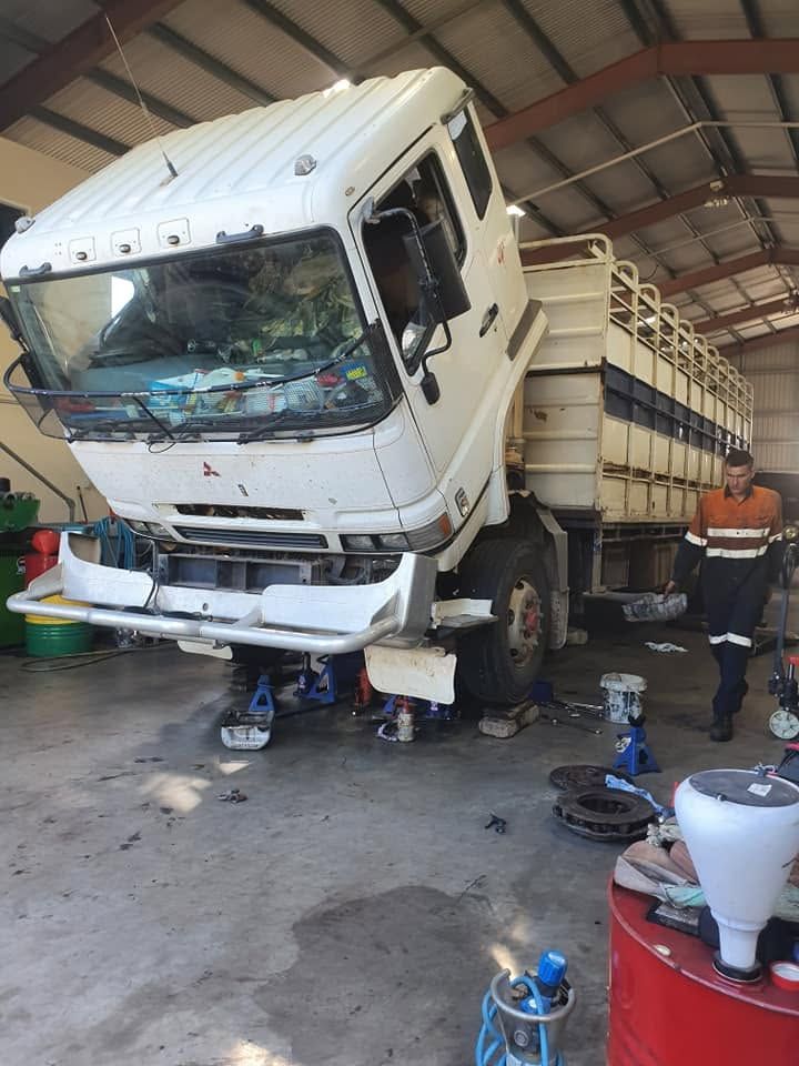 Auto Electrician Gympie Servicing Raised Truck In Workshop