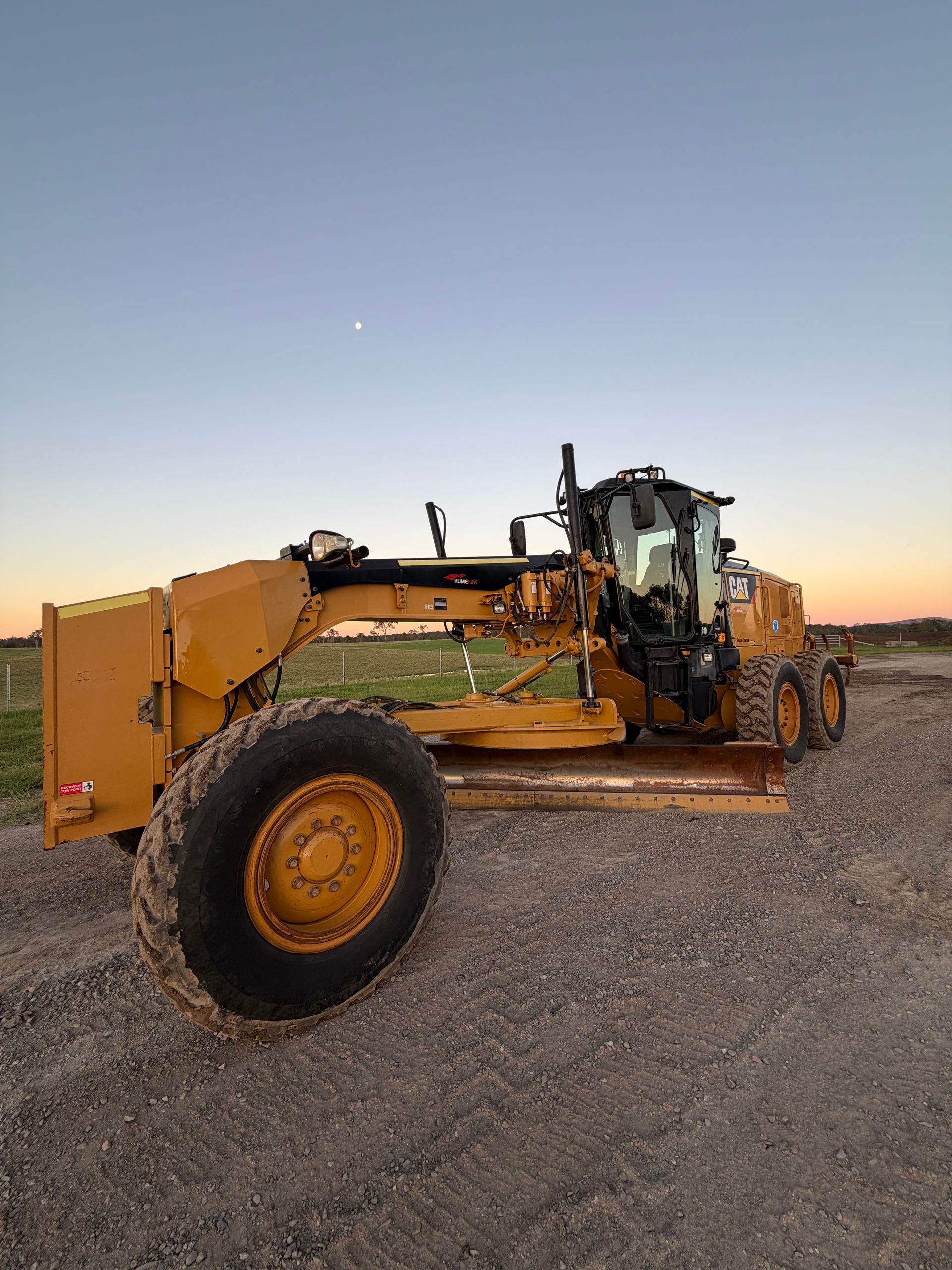 Yellow Grader on Gravel Road Under a Blue Sky, Setting Sun — HOLESHOT Diesel In Rockhampton, QLD