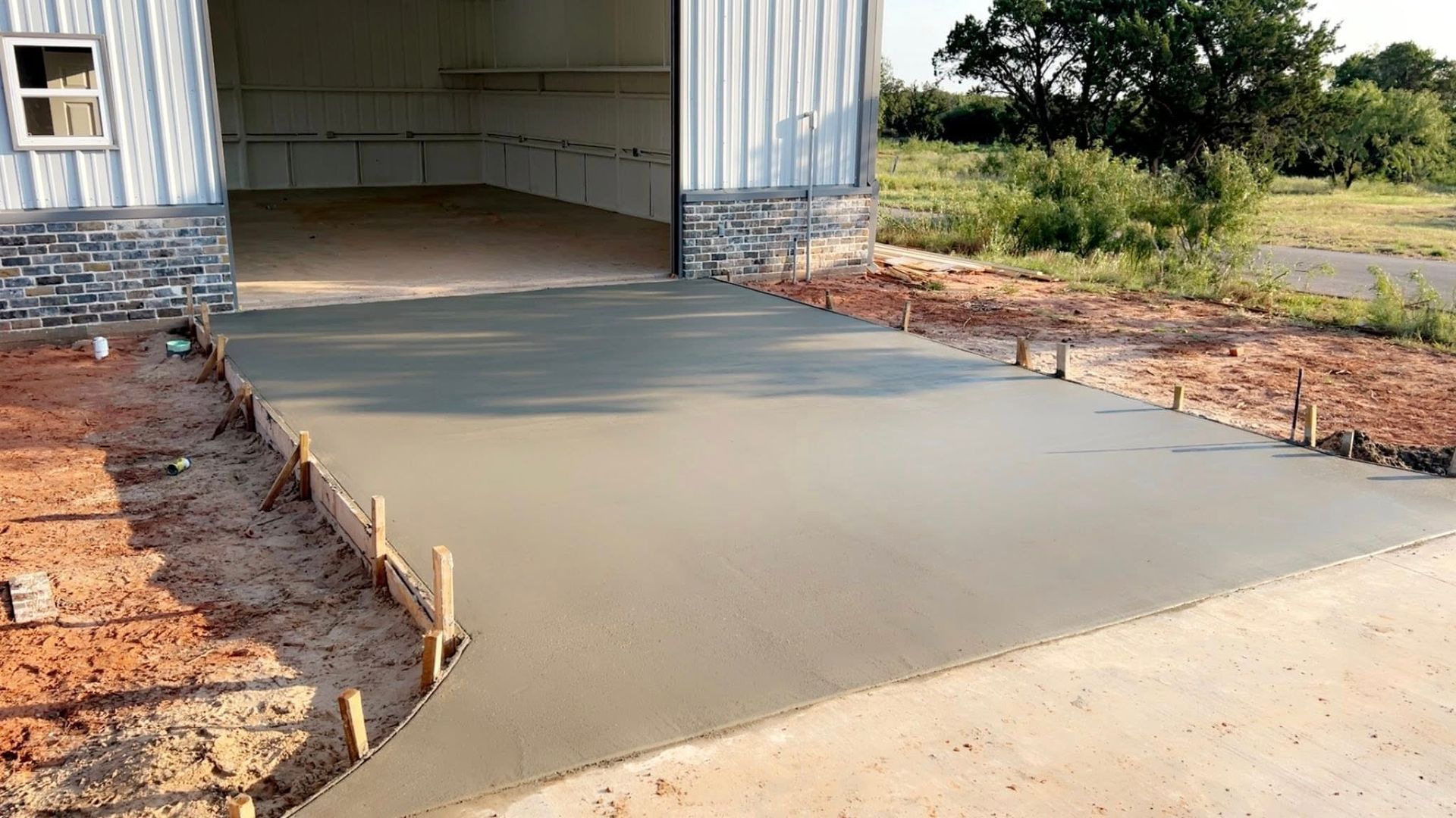 New concrete driveway leading to a garage door, with wooden formwork on the sides.
