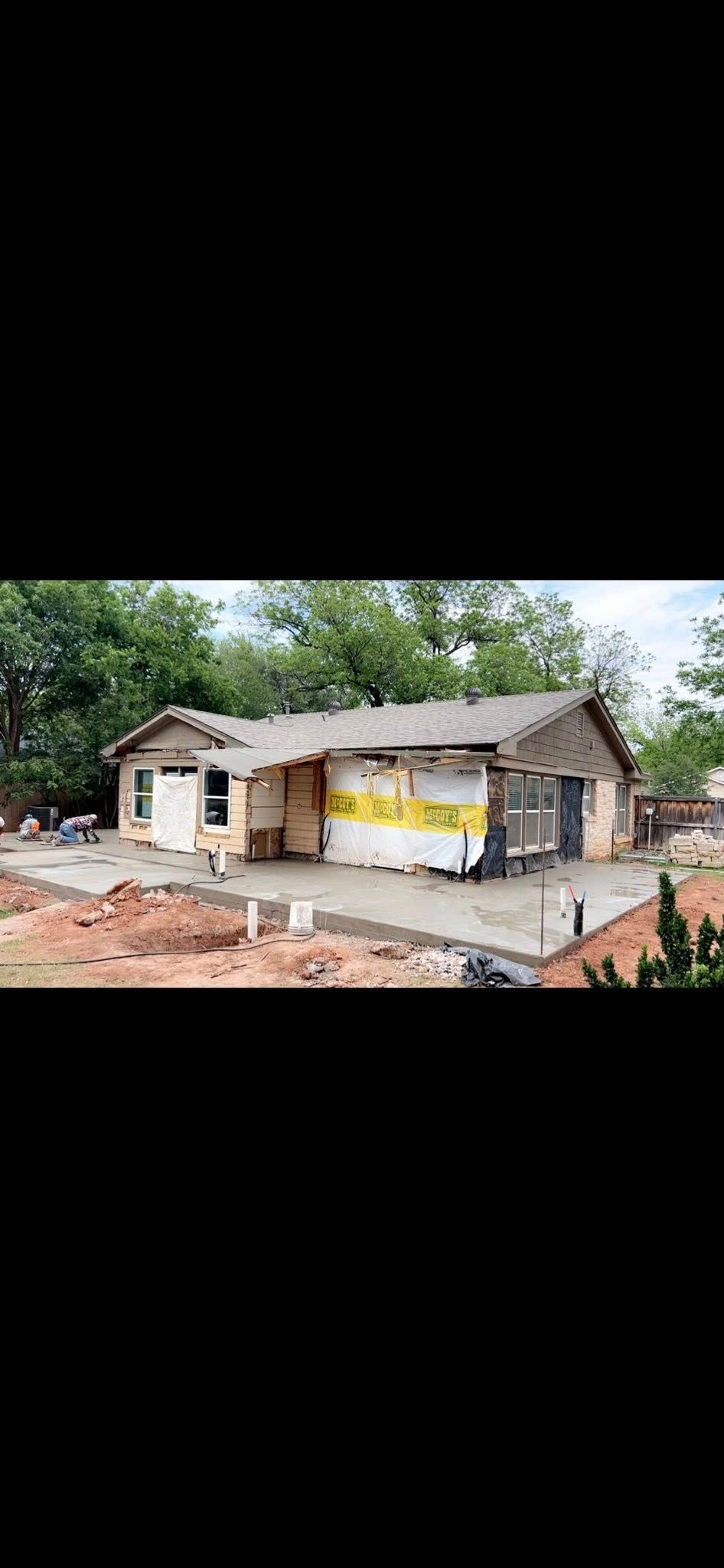 A single-story house under construction with exposed framing and a concrete foundation.