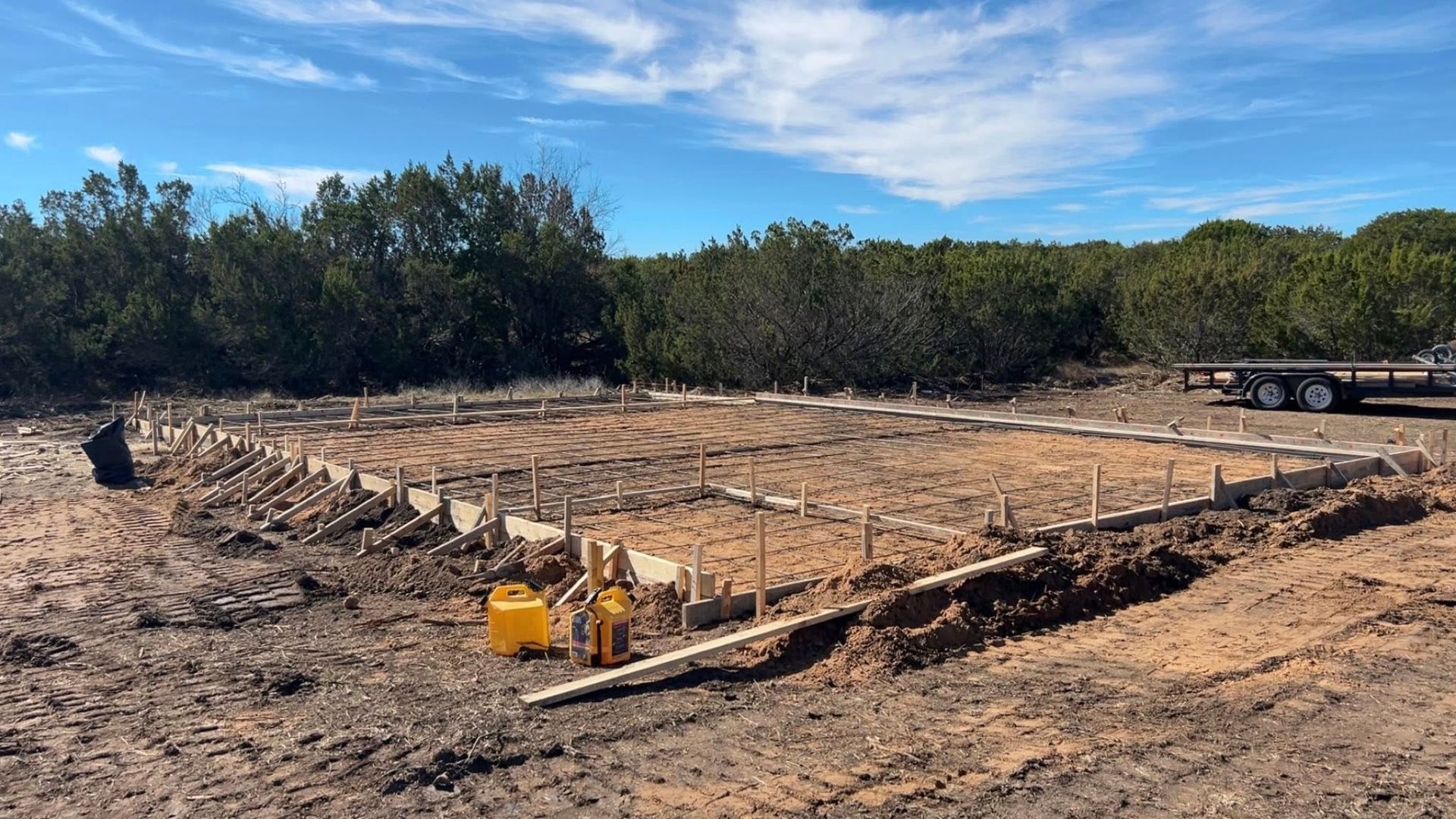 Construction site with wooden forms for a foundation, in an outdoor setting.